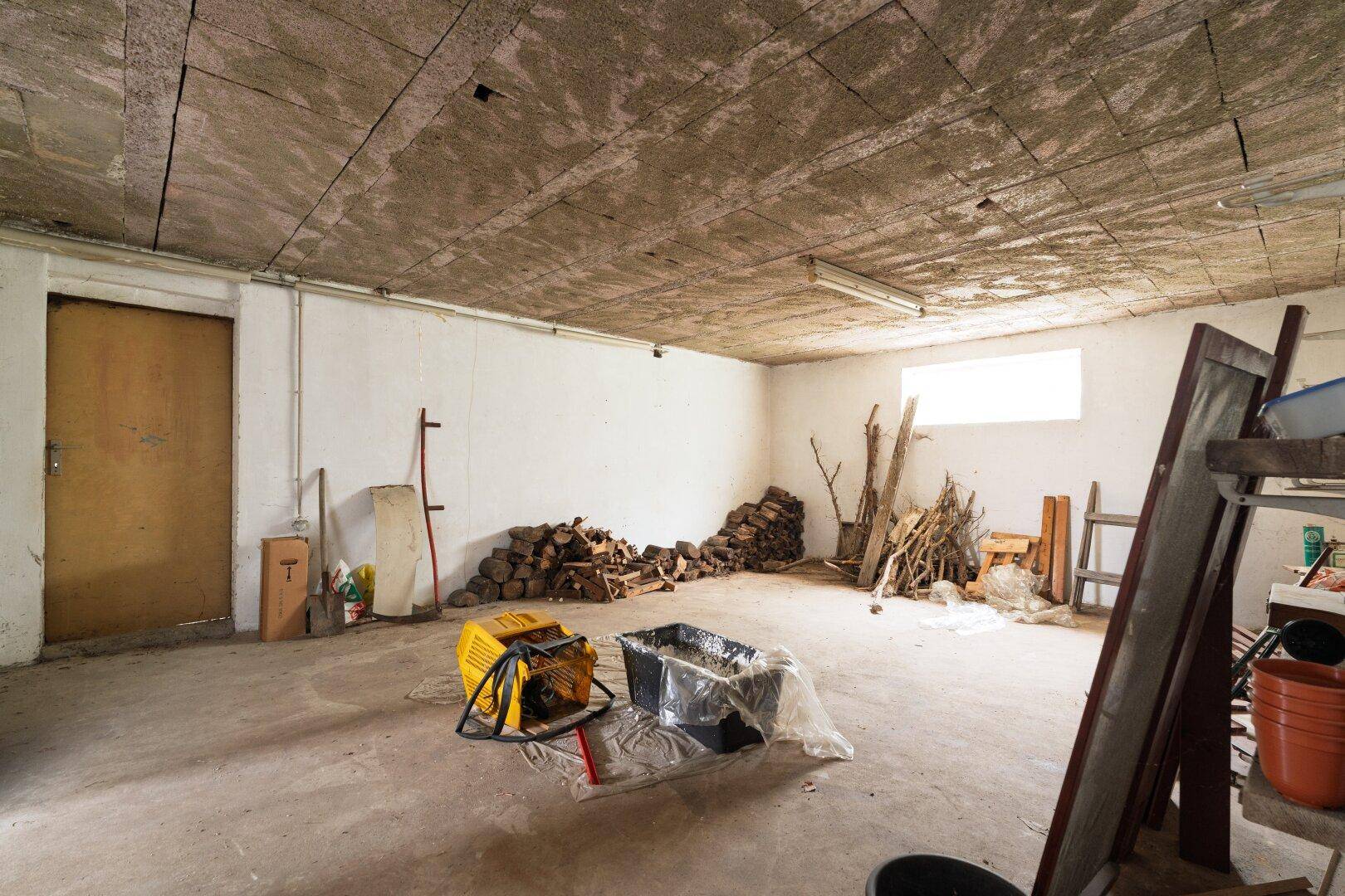 Kellerraum mit Holzstapel und Werkzeugen, geeignet für Lagerung.