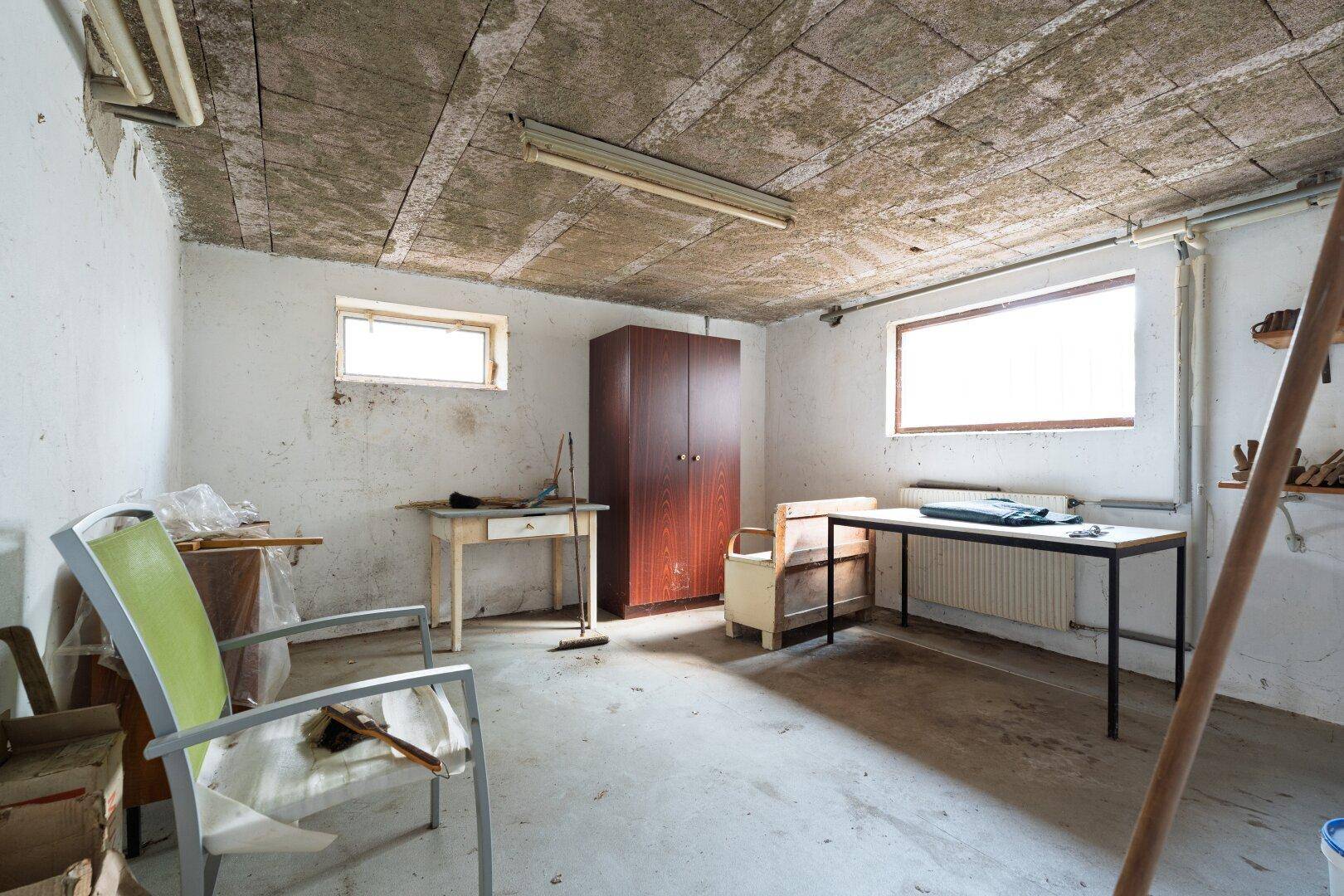 Ausgebauter Kellerraum mit Möbeln und Fenstern, vielseitig nutzbar.
