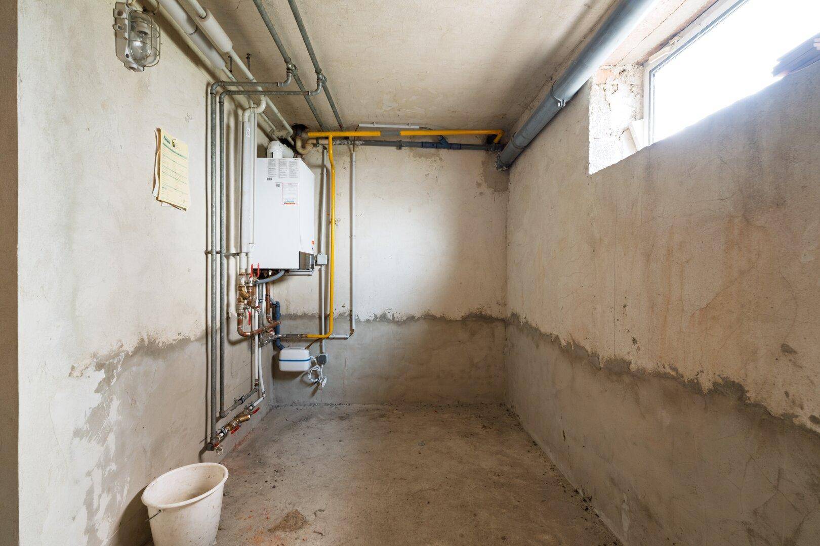 Heizungsraum im Keller mit Gastherme und sichtbaren Rohren.
