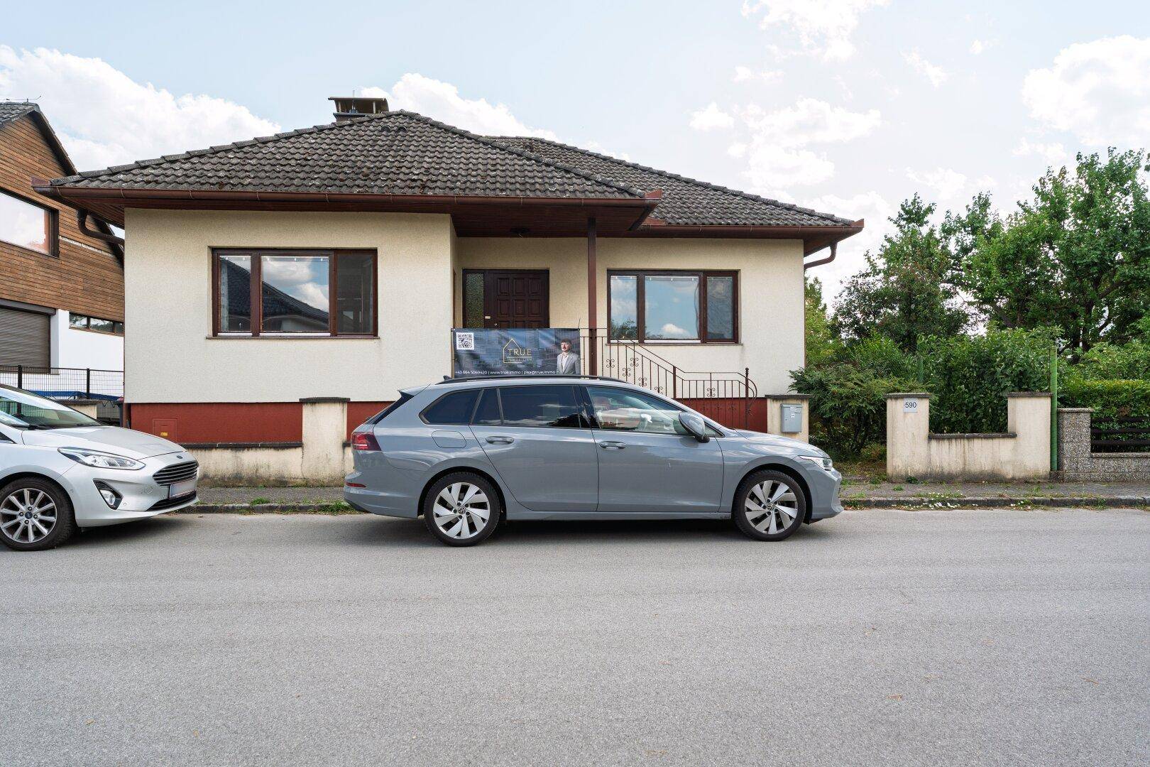 Vorderansicht des Einfamilienhauses von der Straße mit geparkten Autos.