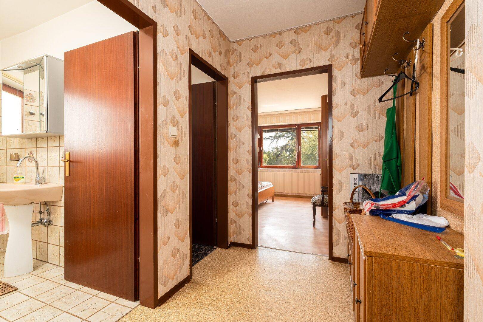 Flur mit gemusterten Tapeten, Zugang zu Bad und Schlafzimmer.