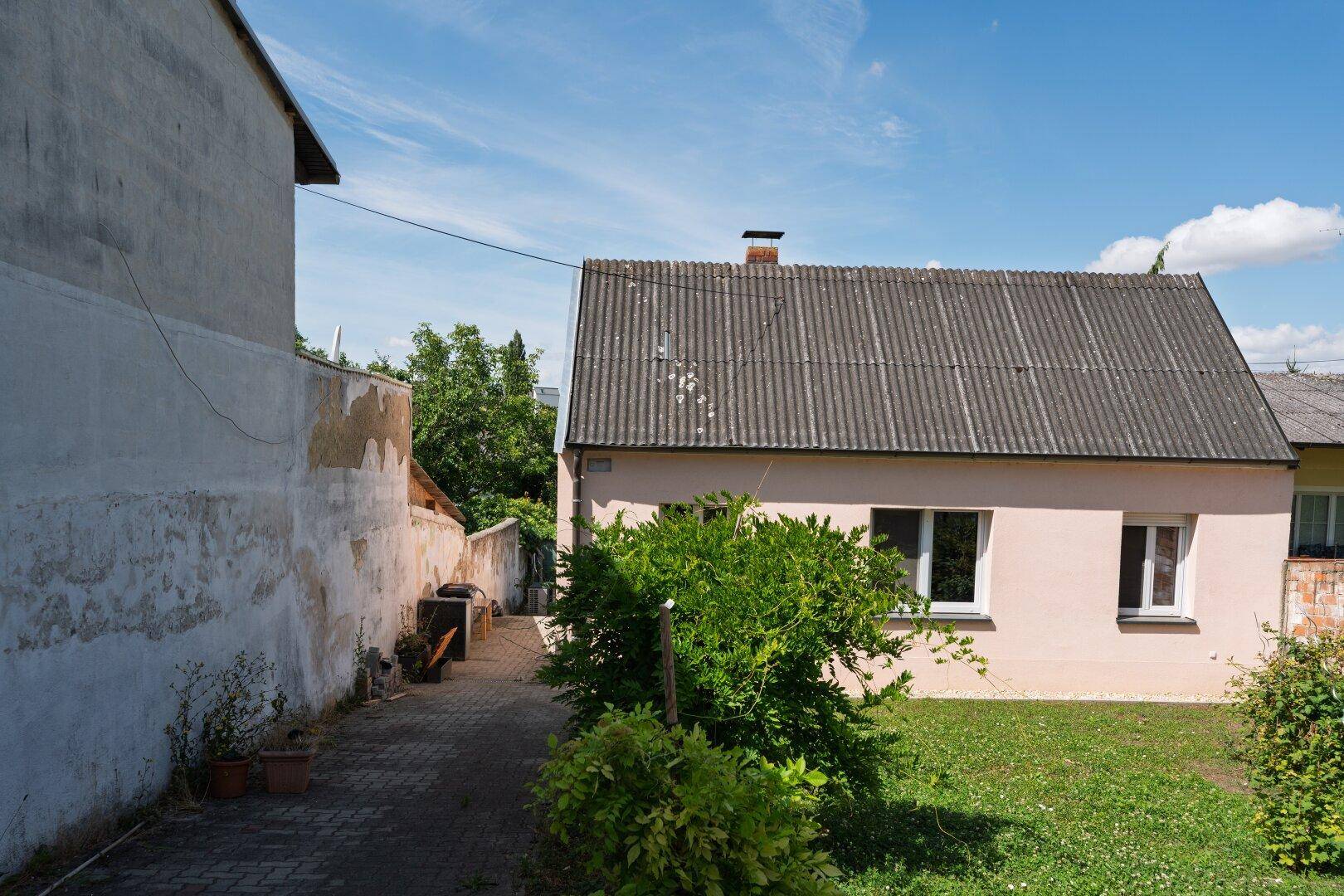 Ansicht des Hauses von der Seite mit gepflasterter Zufahrt und einem kleinen Vorgarten.