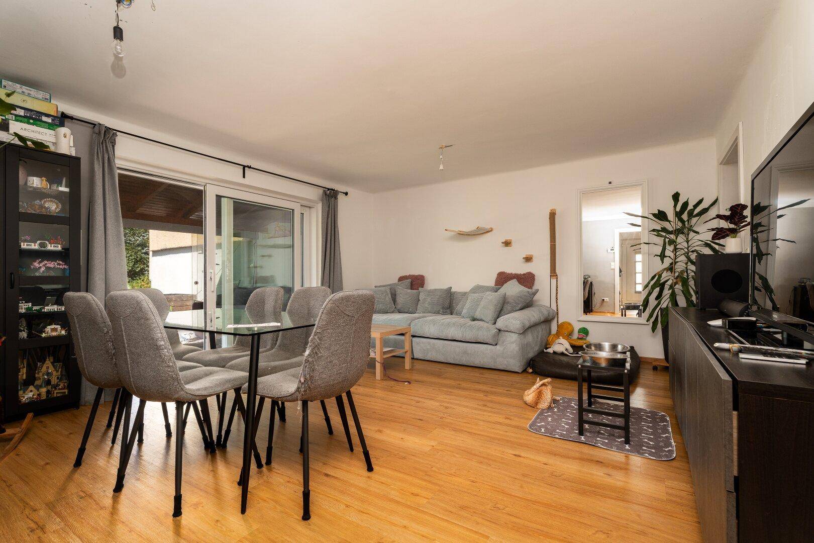 Geräumiger Wohn-Essbereich mit bequemer Couch, Esstisch und Blick auf den Fernseher.