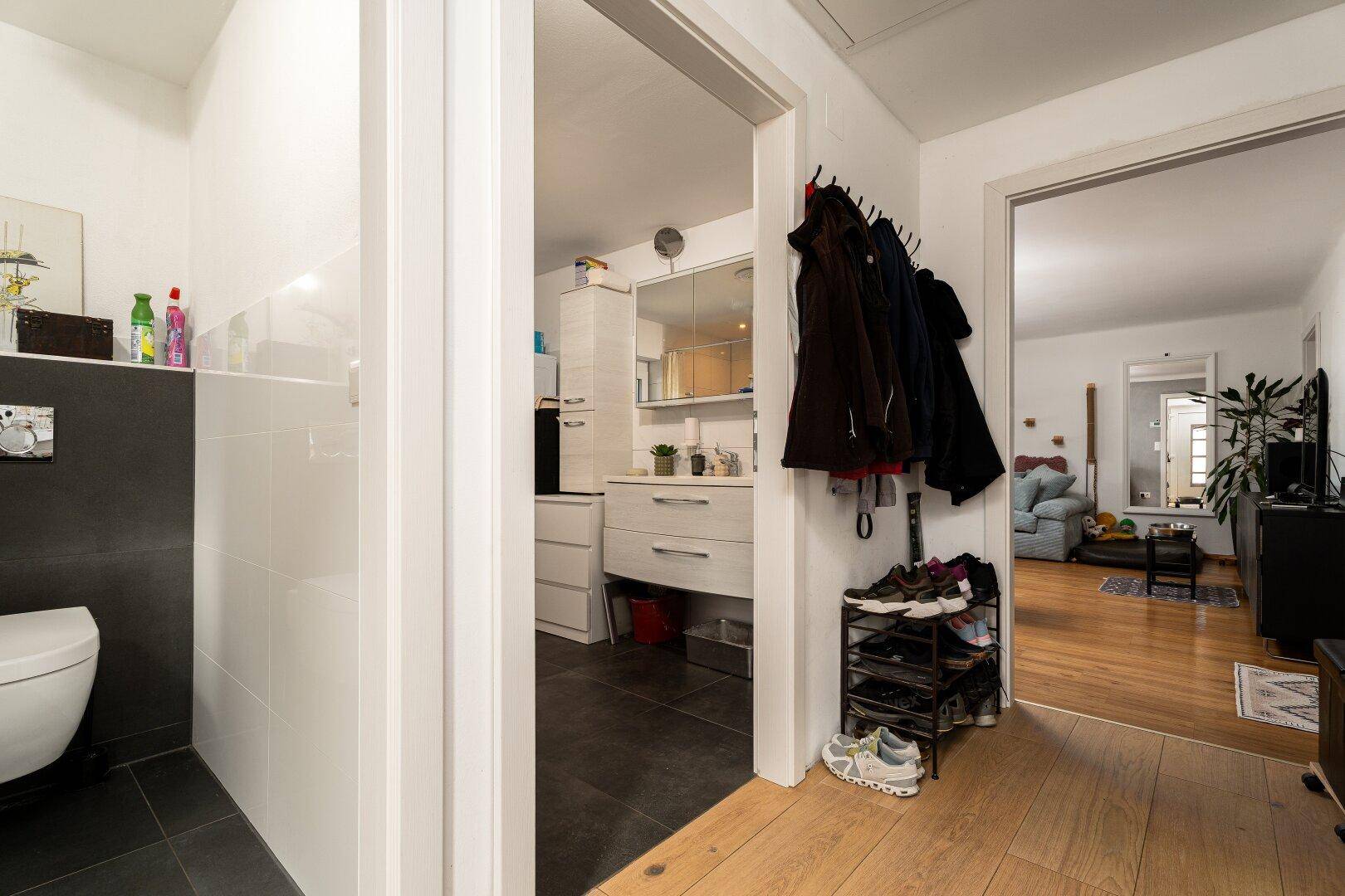 Flur mit Garderobe und Blick in das Gäste-WC sowie den angrenzenden Wohnbereich.