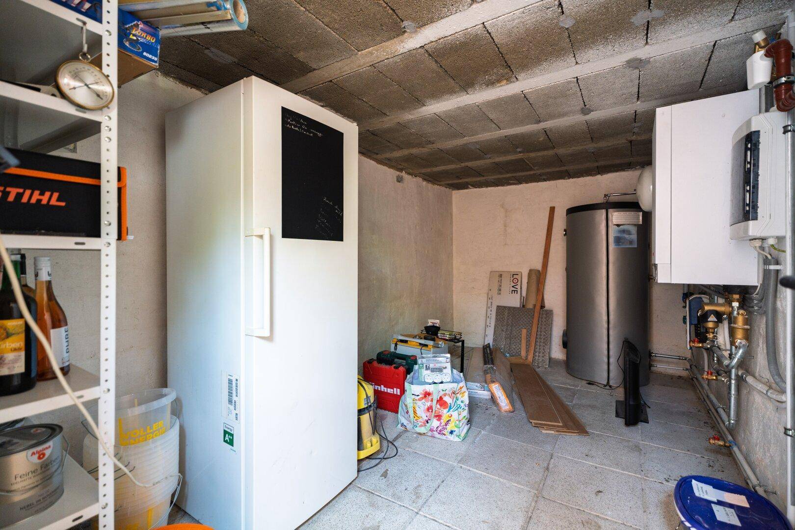Hauswirtschaftsraum im Keller mit Gefrierschrank, Warmwasserspeicher und Regalen für Vorräte.