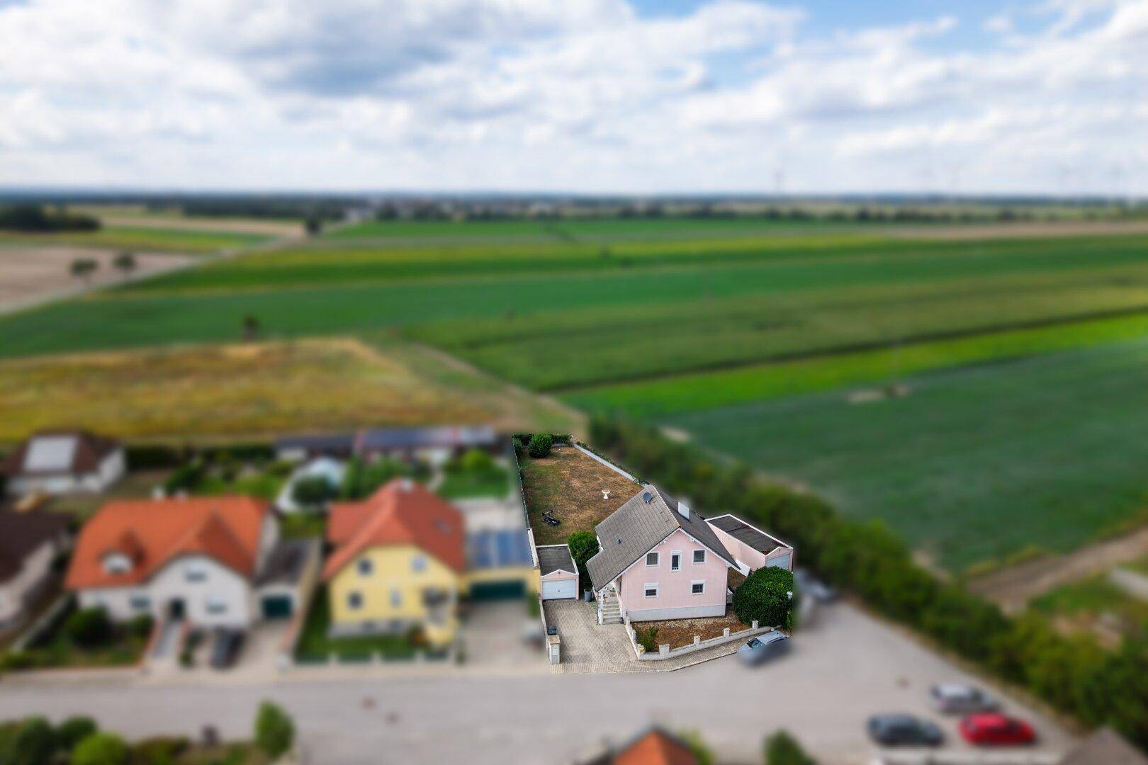 Vogelperspektive des Hauses mit angrenzenden Feldern und der umliegenden Wohnbebauung.