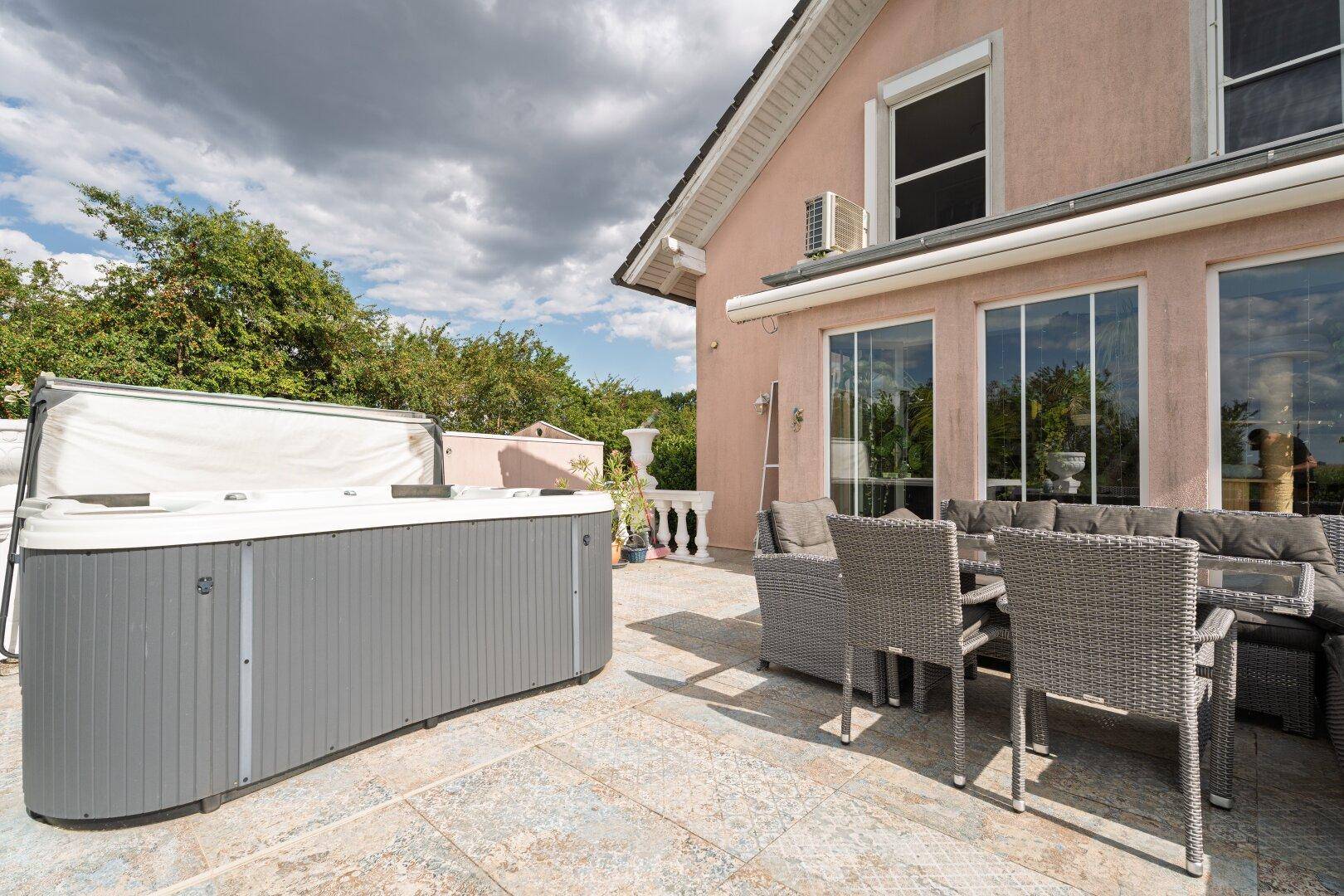 Geräumige Terrasse mit modernen Outdoor-Möbeln und einem entspannenden Whirlpool unter freiem Himmel.