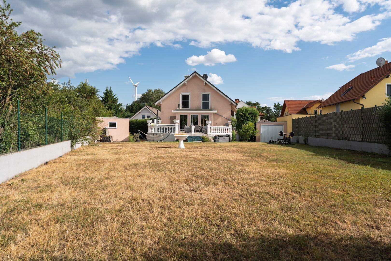 Weitläufiger Gartenbereich mit Rasenfläche und Blick auf das Haus und die Umgebung.