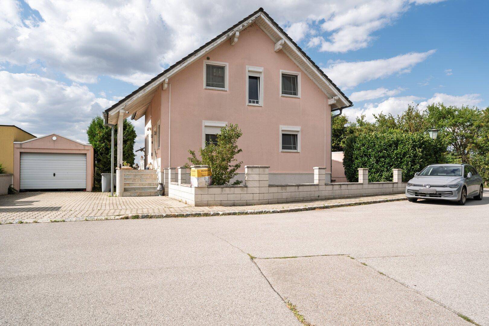 Ansicht des Hauses von der Straße mit gepflasterter Auffahrt und separater Garage.