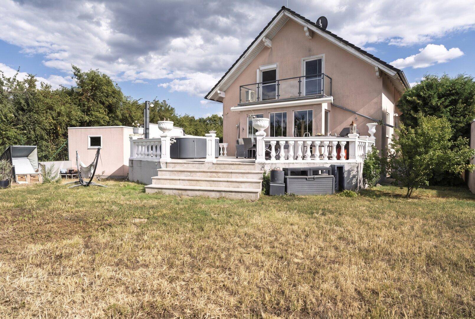 Weitläufiger Garten mit Rasenfläche und einer erhöhten Terrasse, ideal für Entspannung im Freien.