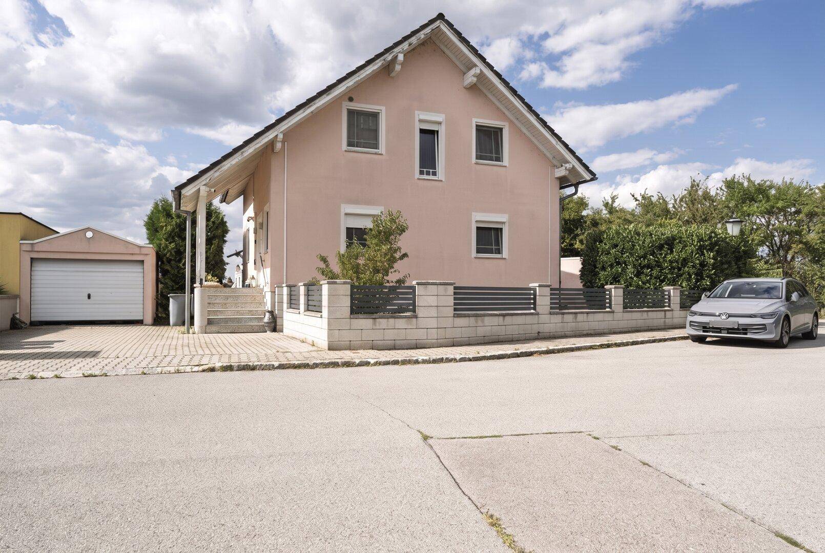 Frontansicht des Einfamilienhauses mit moderner Zaunanlage und Garage.