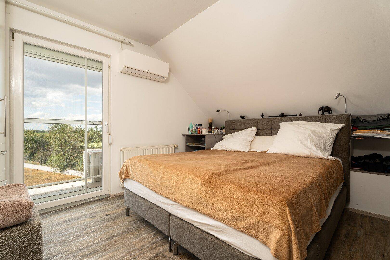 Gemütliches Schlafzimmer mit Doppelbett, Klimaanlage und Zugang zum Balkon.