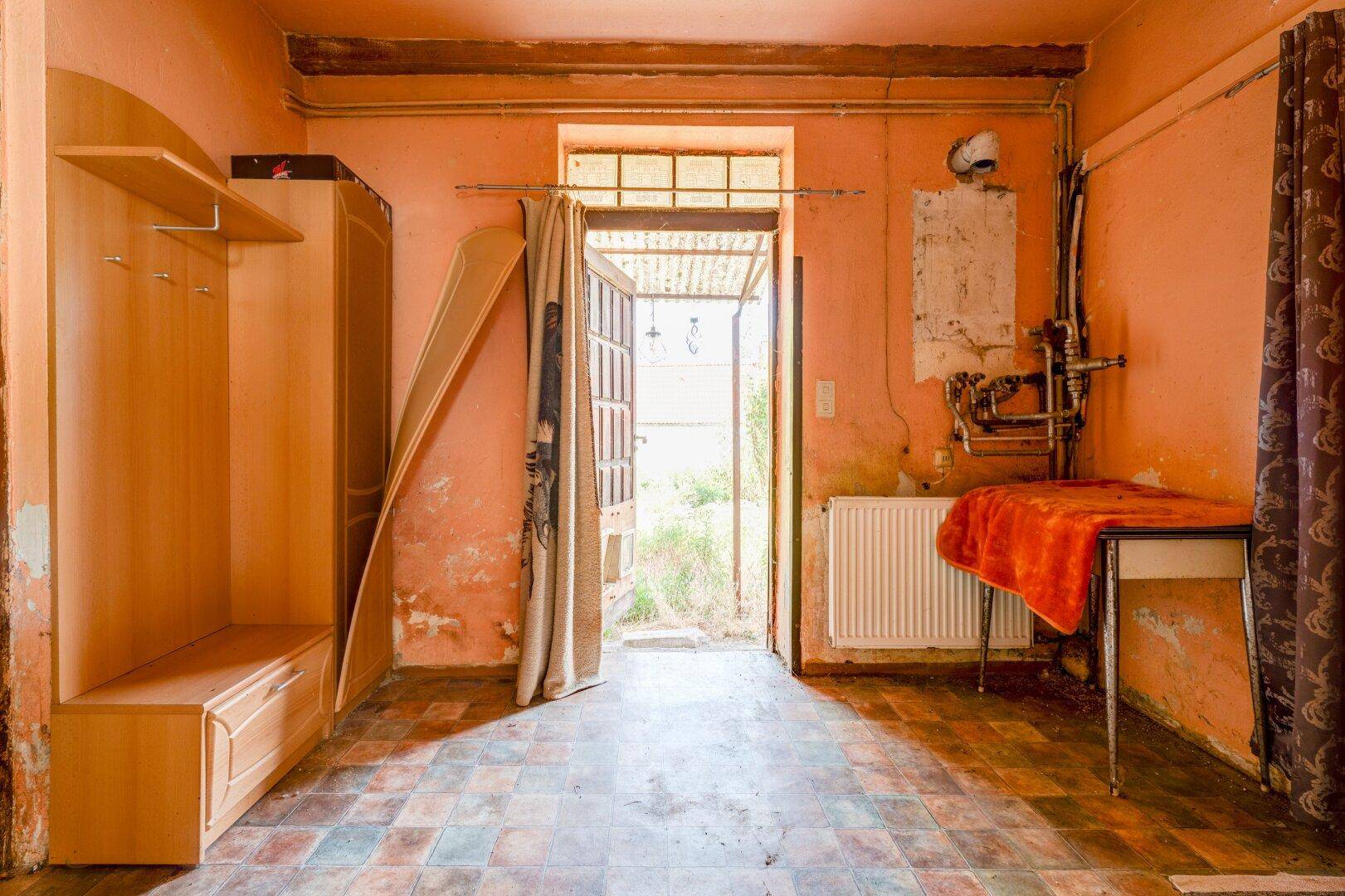 Eingangsbereich oder Flur mit Garderobe, Heizkörper und Fliesenboden, mit Blick nach draußen.