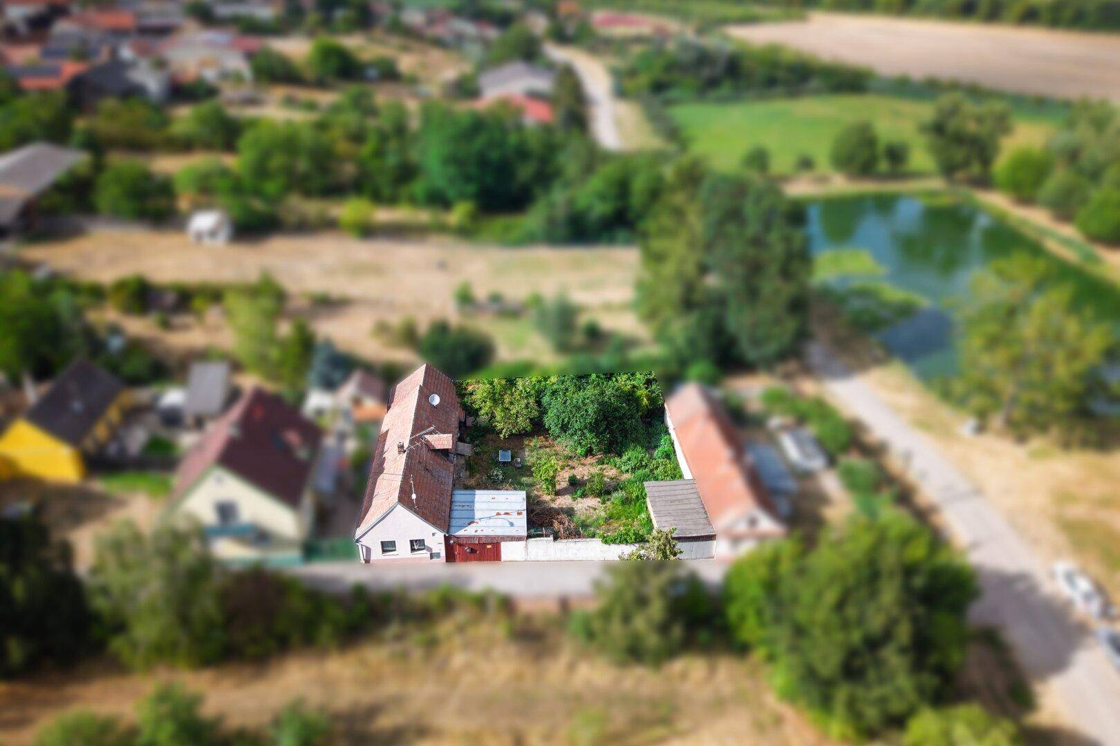 Luftaufnahme des Anwesens mit einem Teich in der Ferne und ländlicher Umgebung.