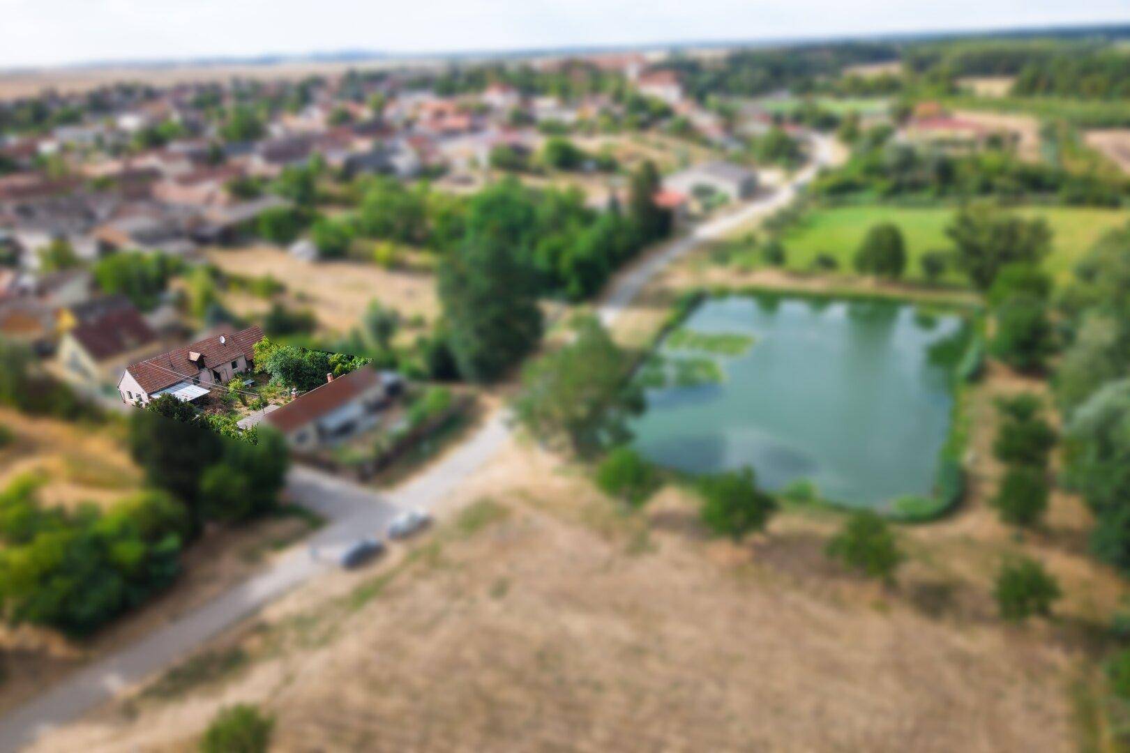 Luftaufnahme des Anwesens und des Dorfes mit einem großen Teich in der ländlichen Umgebung.