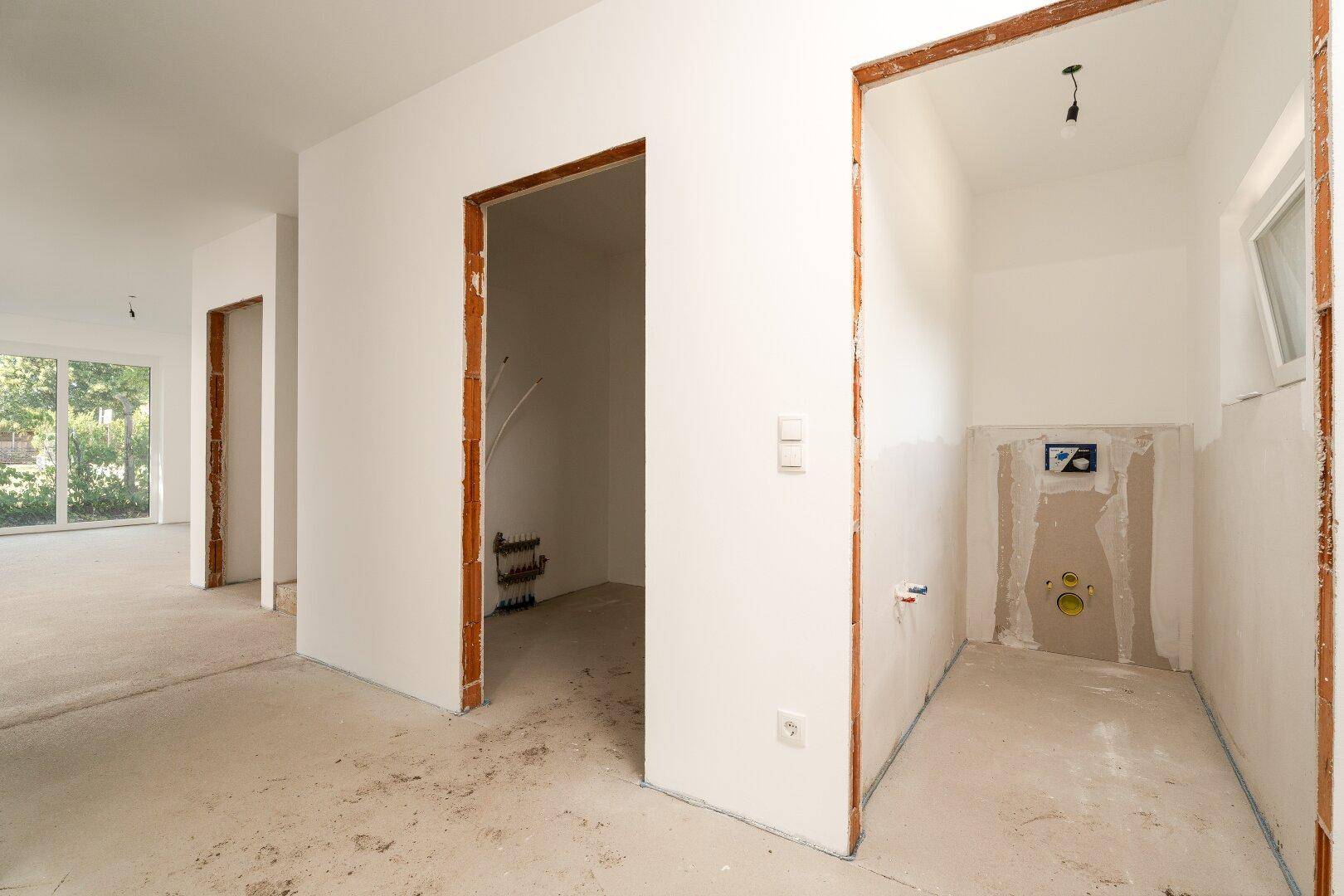 Unfertiger Raum mit sichtbaren Sanitärinstallationen für ein zukünftiges WC oder Badezimmer.