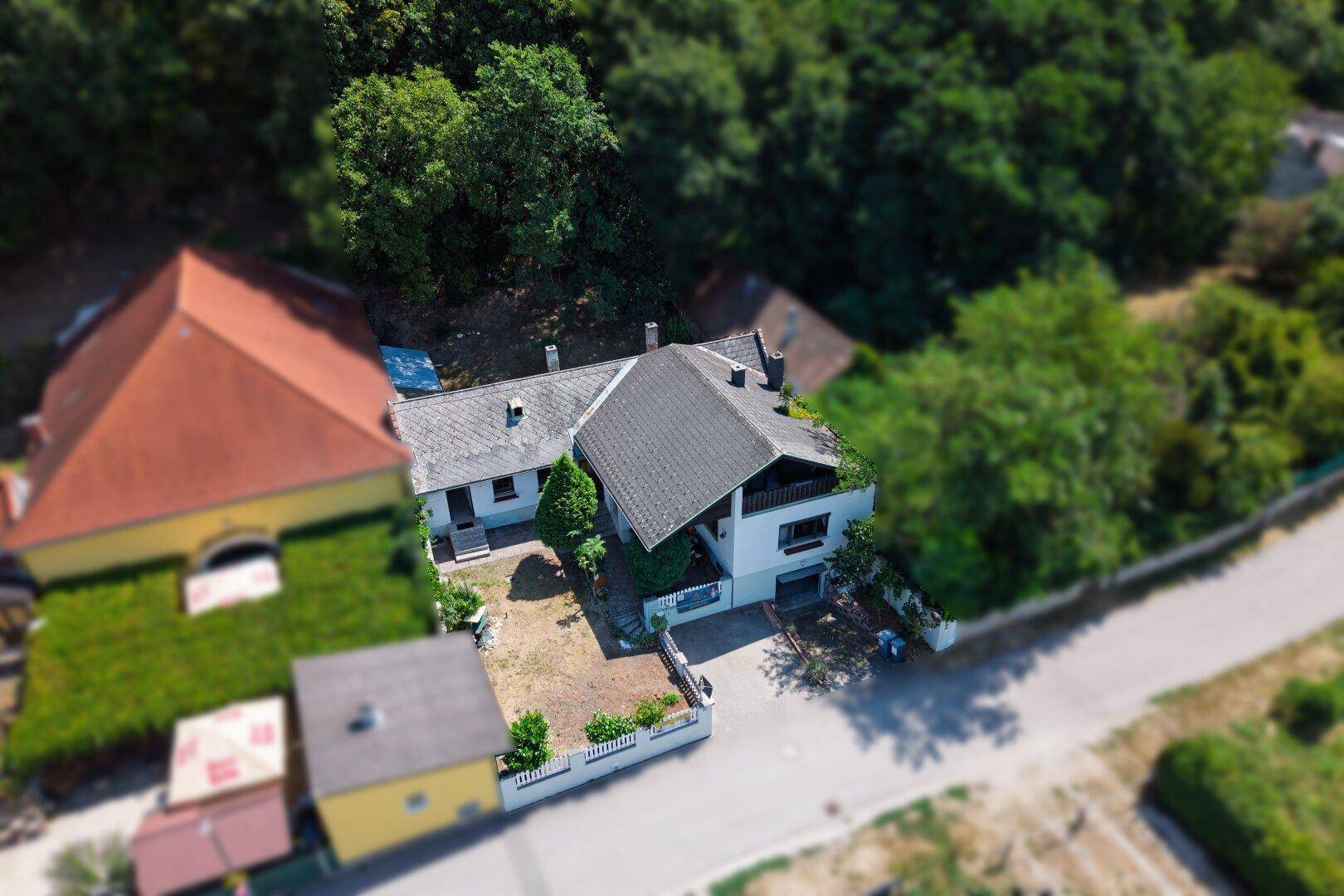Übersichtliche Luftaufnahme des Anwesens mit Haus, Garten und angrenzendem Waldgebiet.