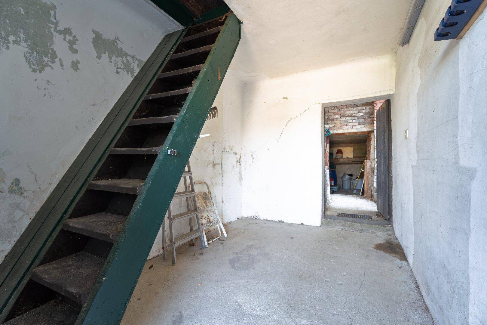 Unausgebauter Kellerraum mit Betontreppe und rohen Wänden, bietet Stauraum.