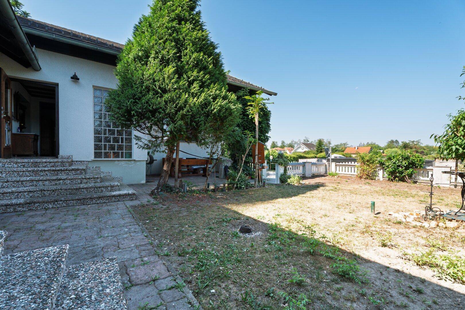 Sonniger Gartenbereich mit Rasenfläche und Bäumen, bietet Platz für Erholung im Freien.
