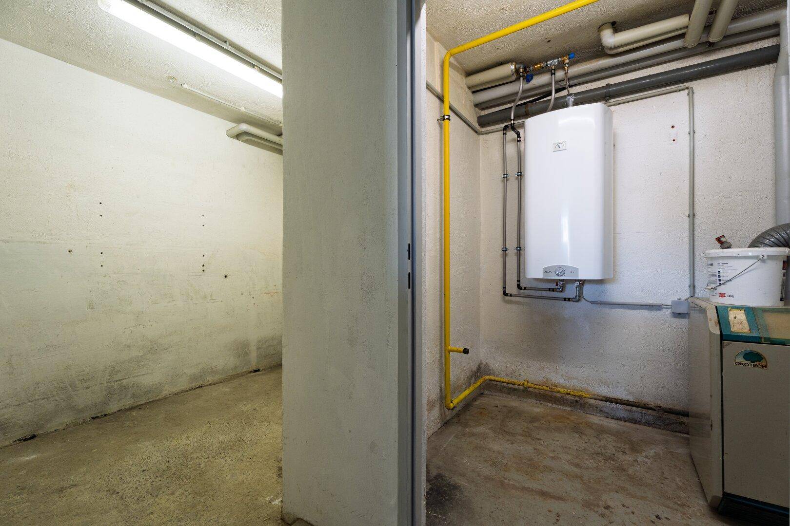 Funktionaler Hauswirtschaftsraum mit Warmwasserbereiter und sichtbaren Leitungen, bietet praktischen Stauraum.