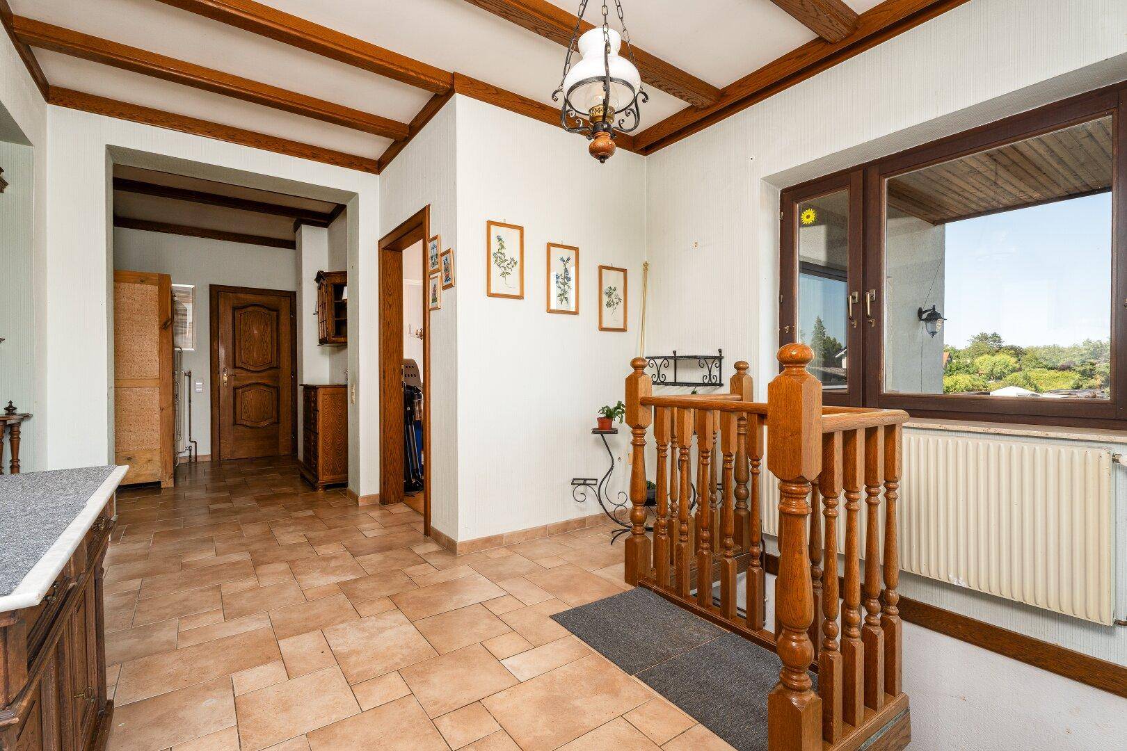 Heller Flur mit Holzdeckenbalken, Fliesenboden und Treppenaufgang in traditionellem Stil.