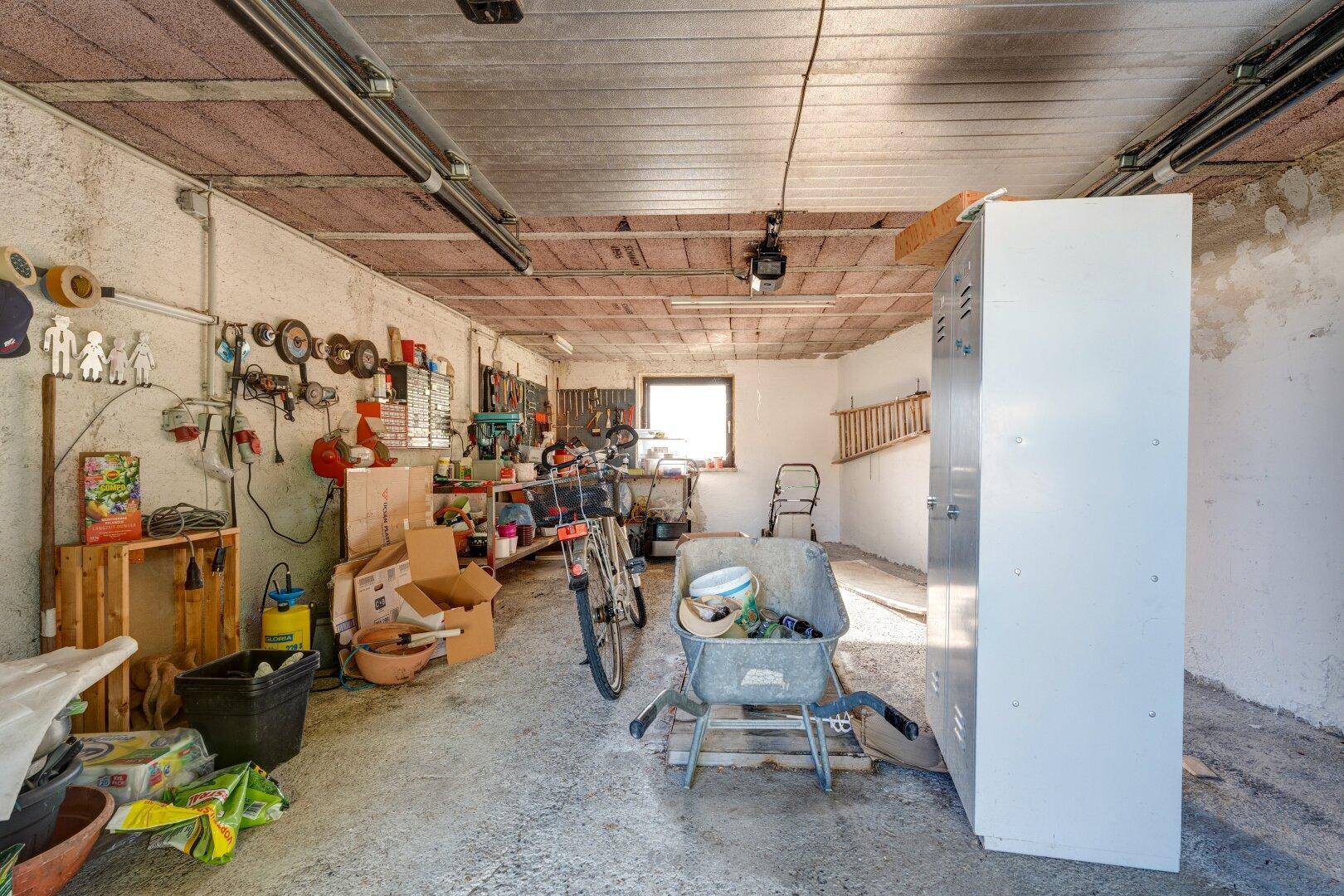 Geräumige Garage mit Werkzeugen, Fahrrädern und Lagerfläche, ideal für Hobby und Abstellzwecke.