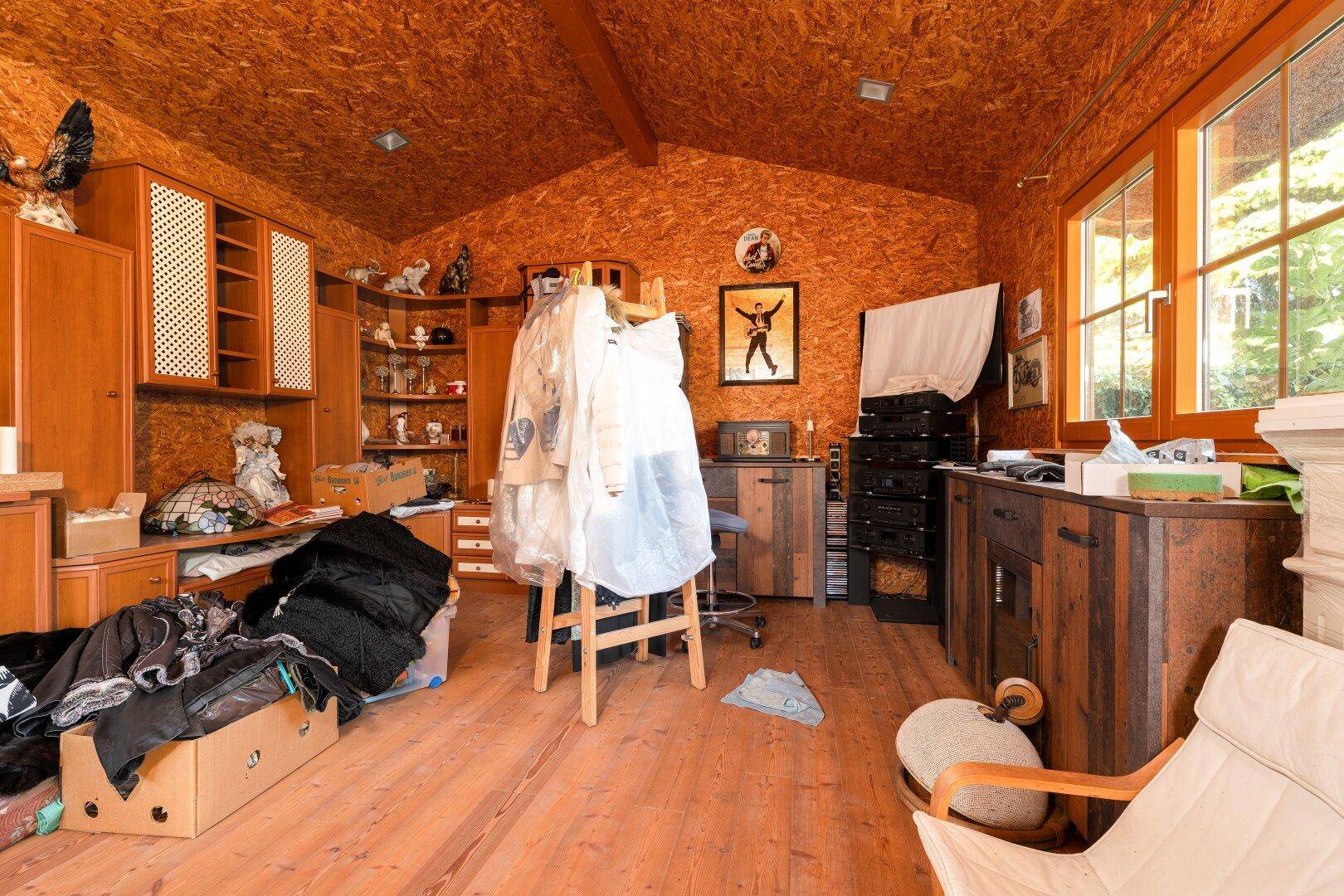 Dachzimmer mit Holzverkleidung, schrägen Decken und viel Stauraum, genutzt als Hobbyraum.