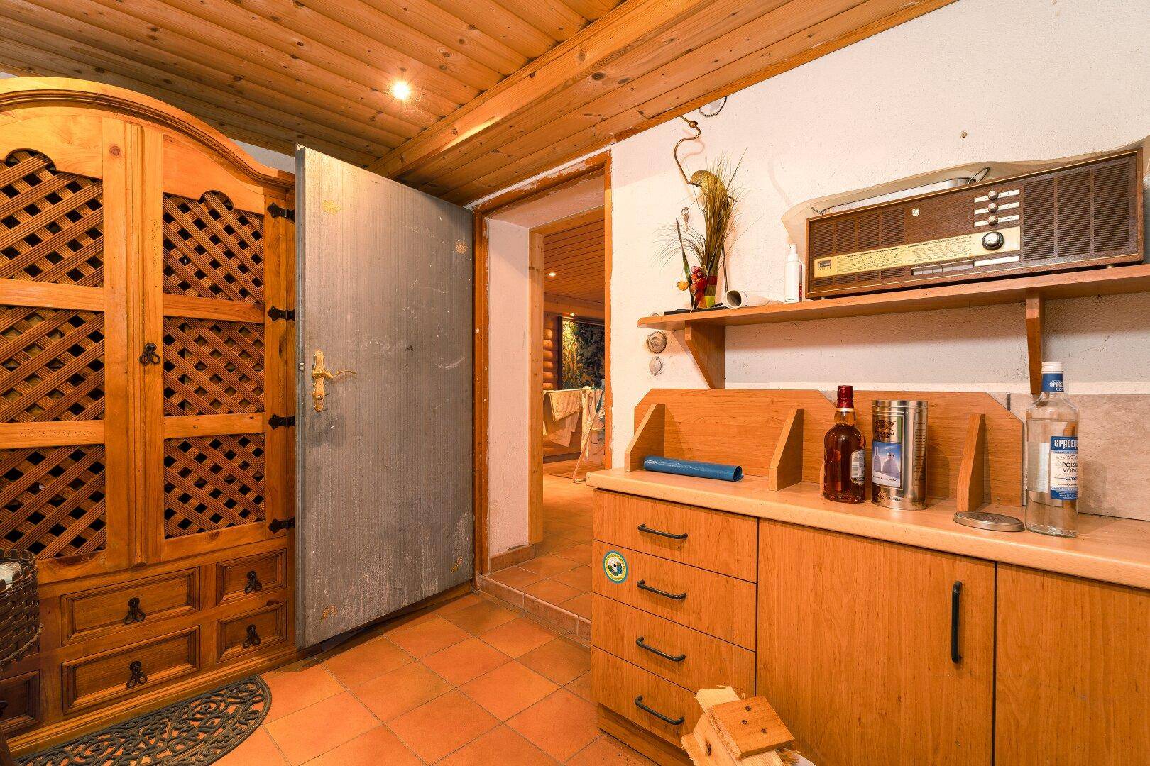 Flur im Kellerbereich mit rustikalem Holzschrank und einer robusten Stahltür, sehr praktisch.
