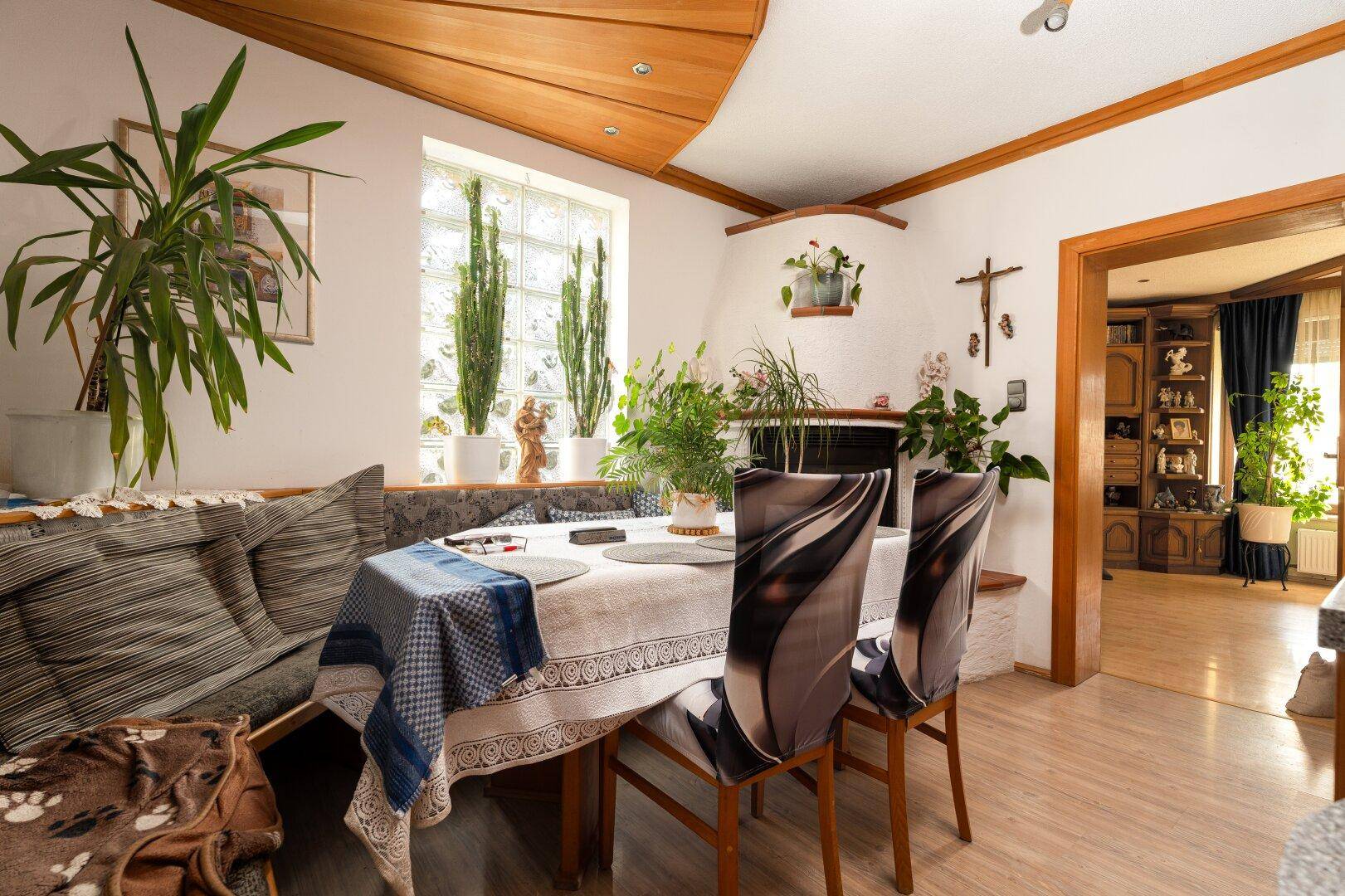 Heller Essbereich mit Holztisch, Eckbank und Blick in den Wohnbereich, umgeben von Pflanzen.