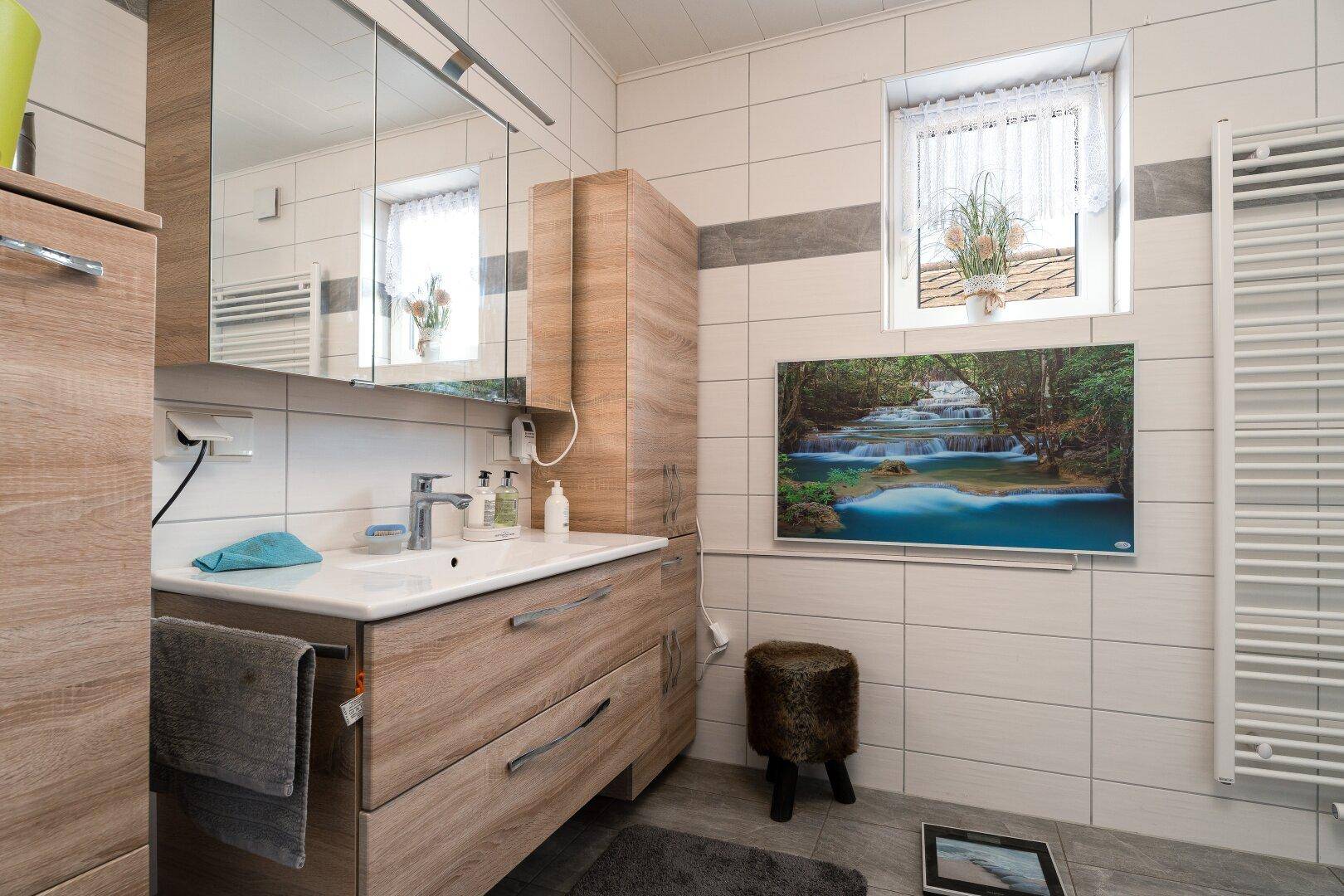 Modernes Badezimmer mit Holzwaschtisch, Spiegelschrank und Fenster für natürliches Licht.