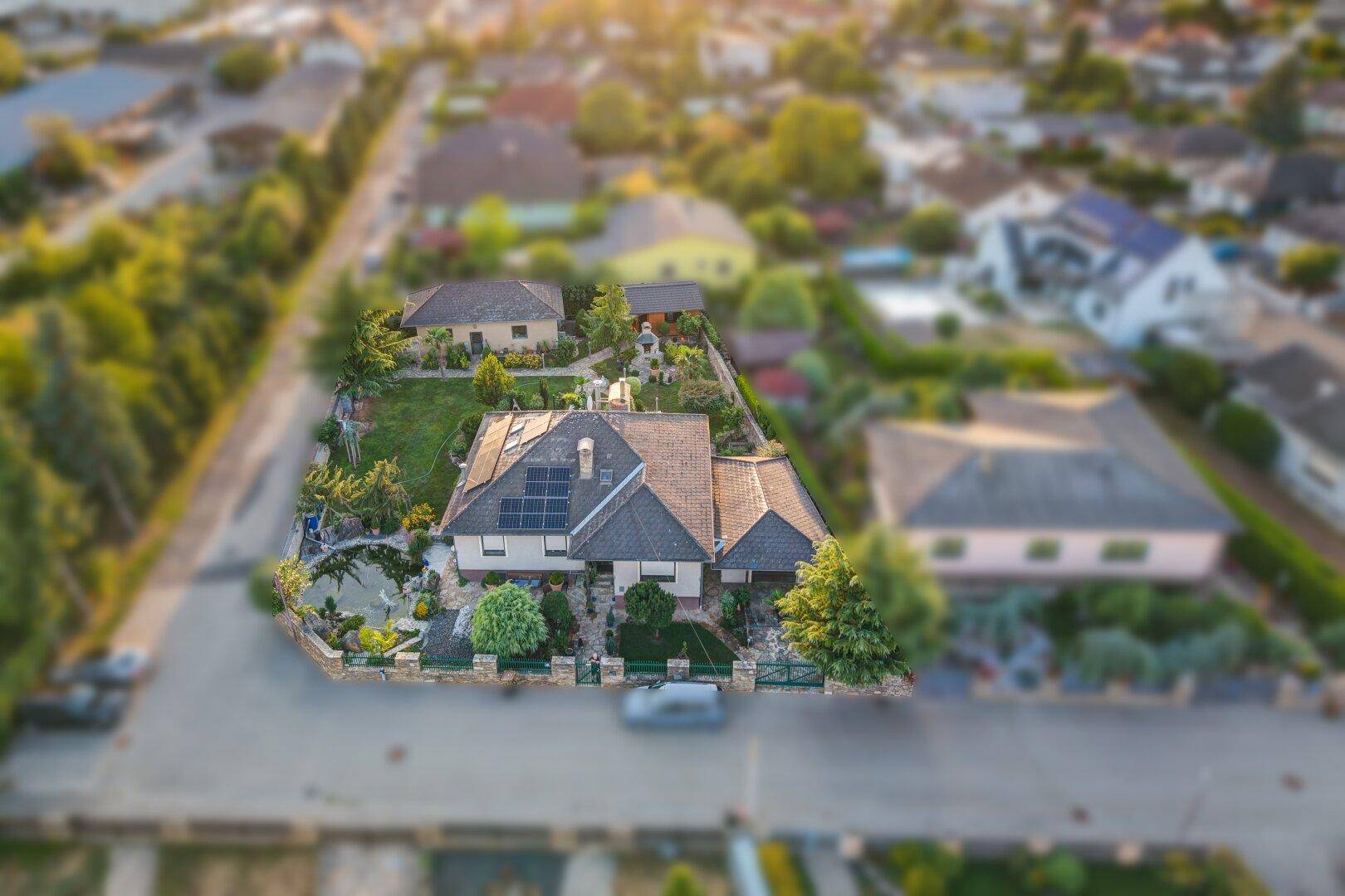 Vogelperspektive eines Einfamilienhauses mit gepflegtem Garten und Solaranlage auf dem Dach.