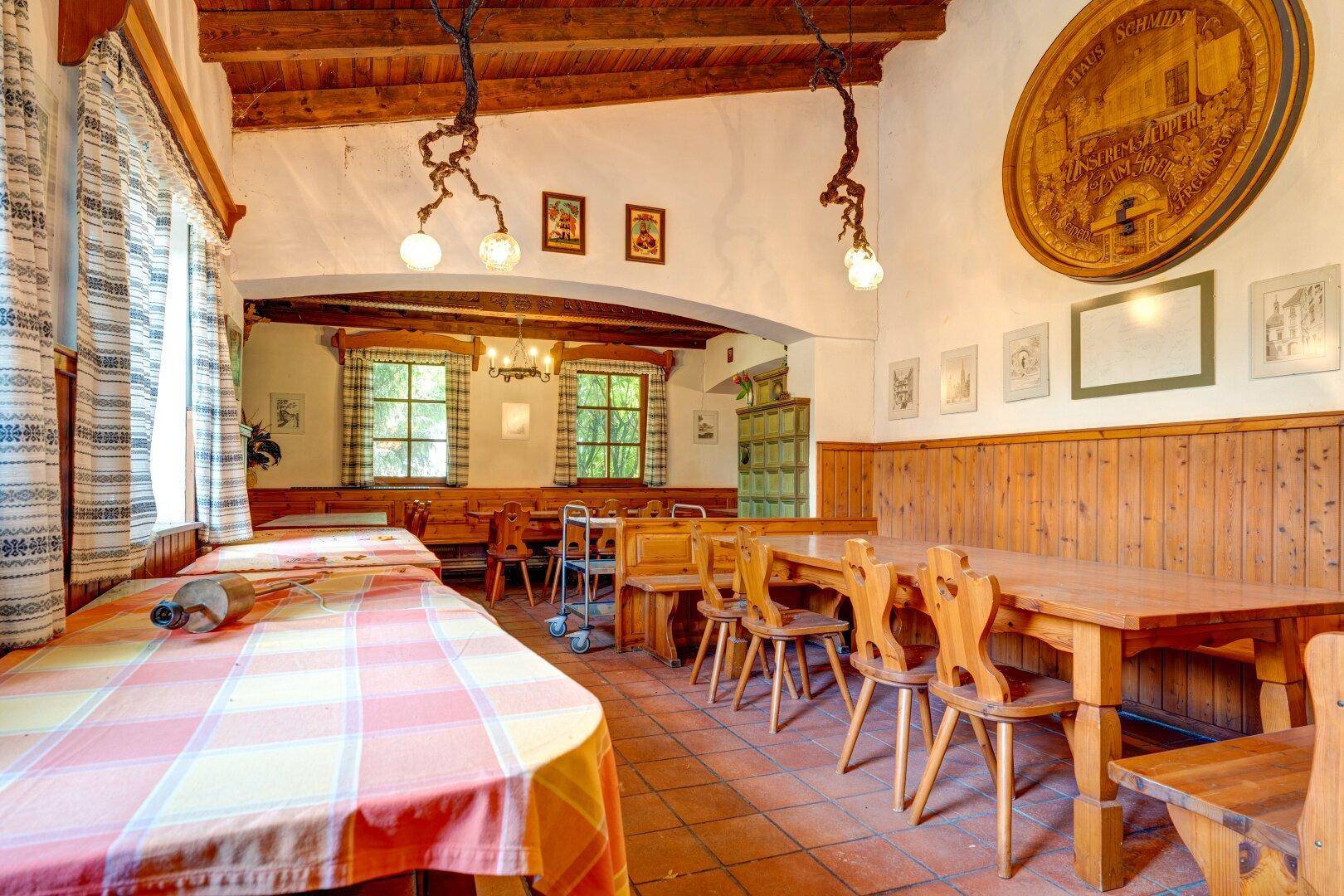 Gemütlicher Speisesaal mit karierten Tischdecken, Holzmöbeln und traditioneller Dekoration an den Wänden.