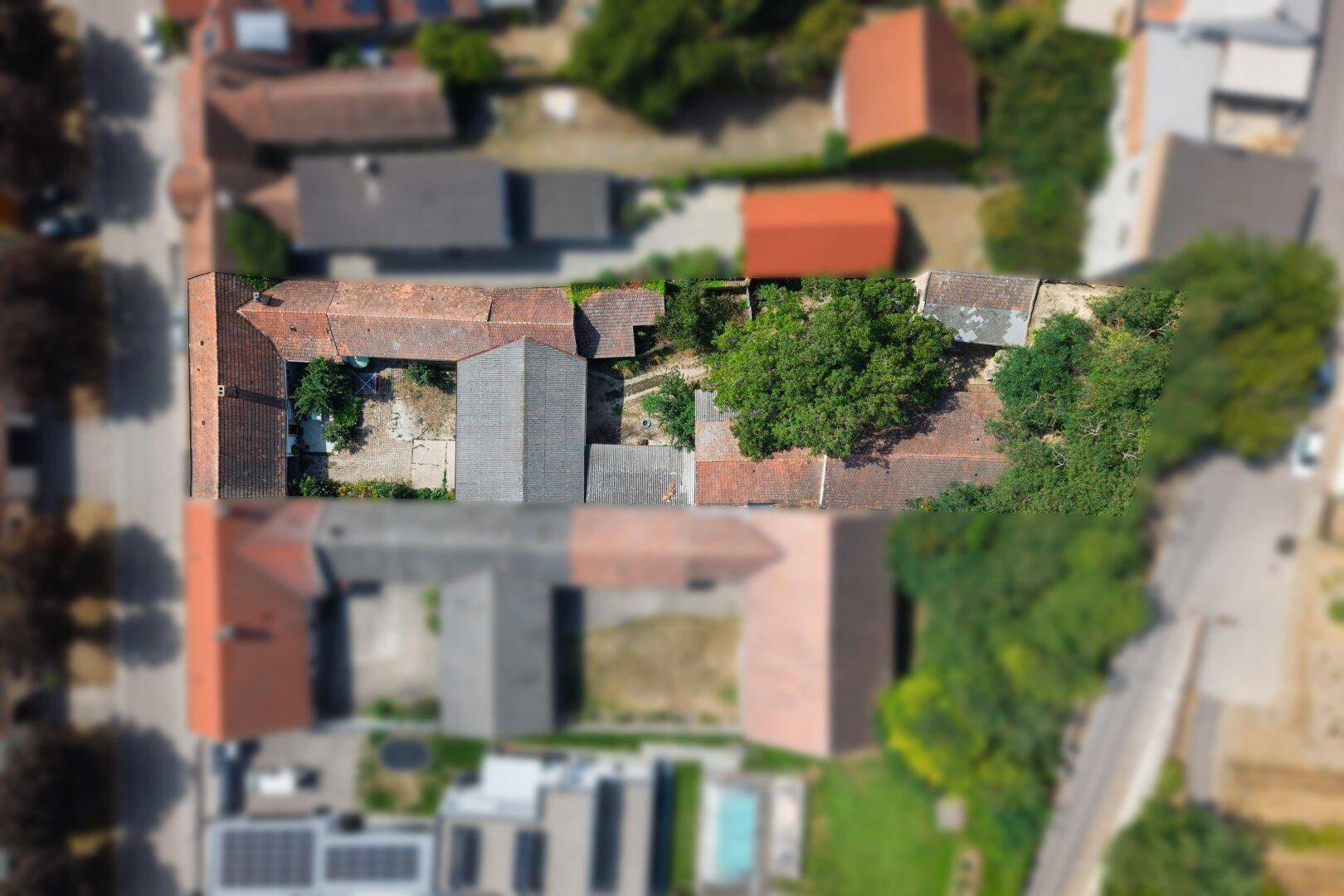Senkrechte Luftaufnahme eines weitläufigen Anwesens mit mehreren Gebäuden und Innenhöfen.