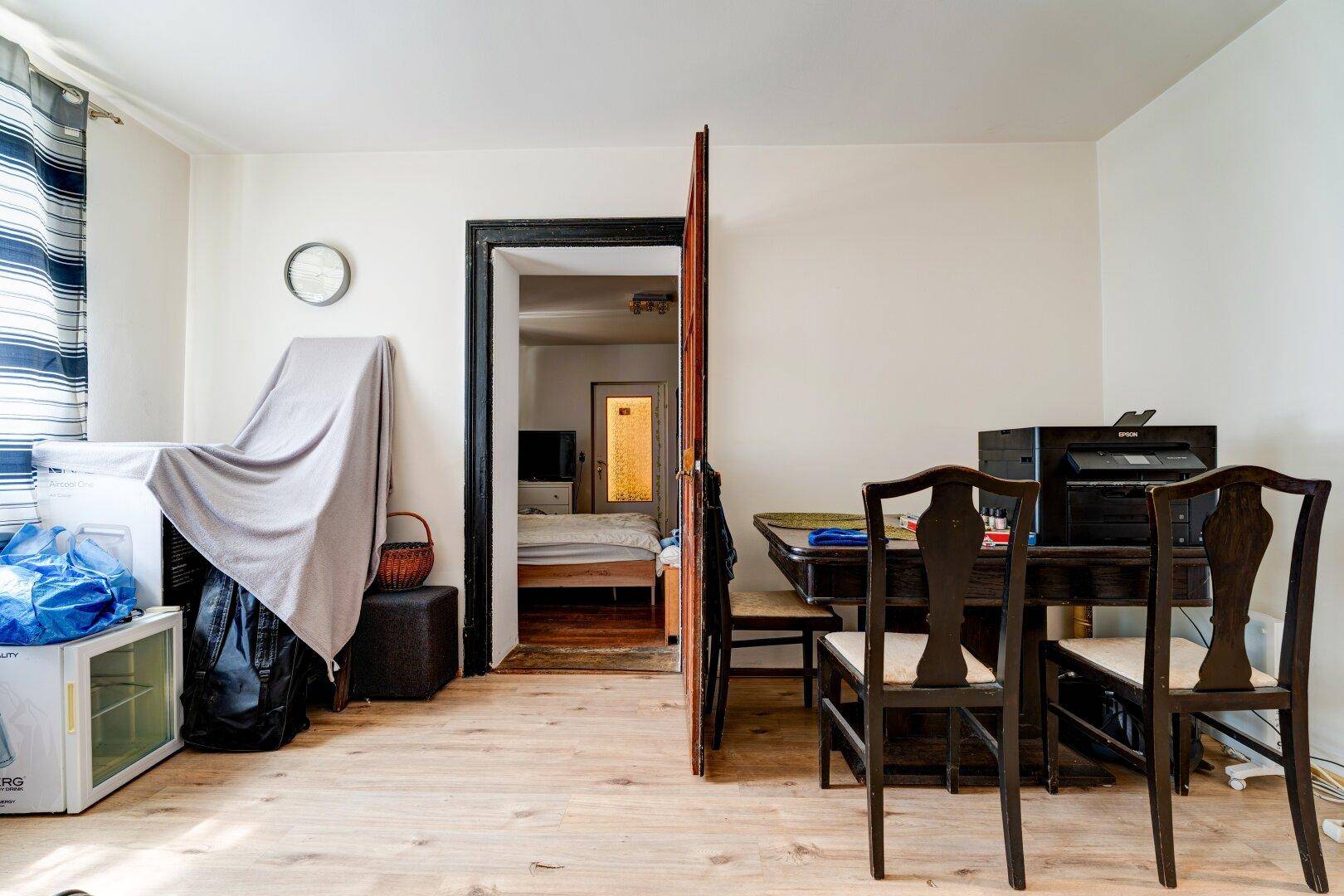Offener Wohnbereich mit Holzboden und Blick in ein angrenzendes Schlafzimmer, das eine fließende Raumgestaltung bietet.