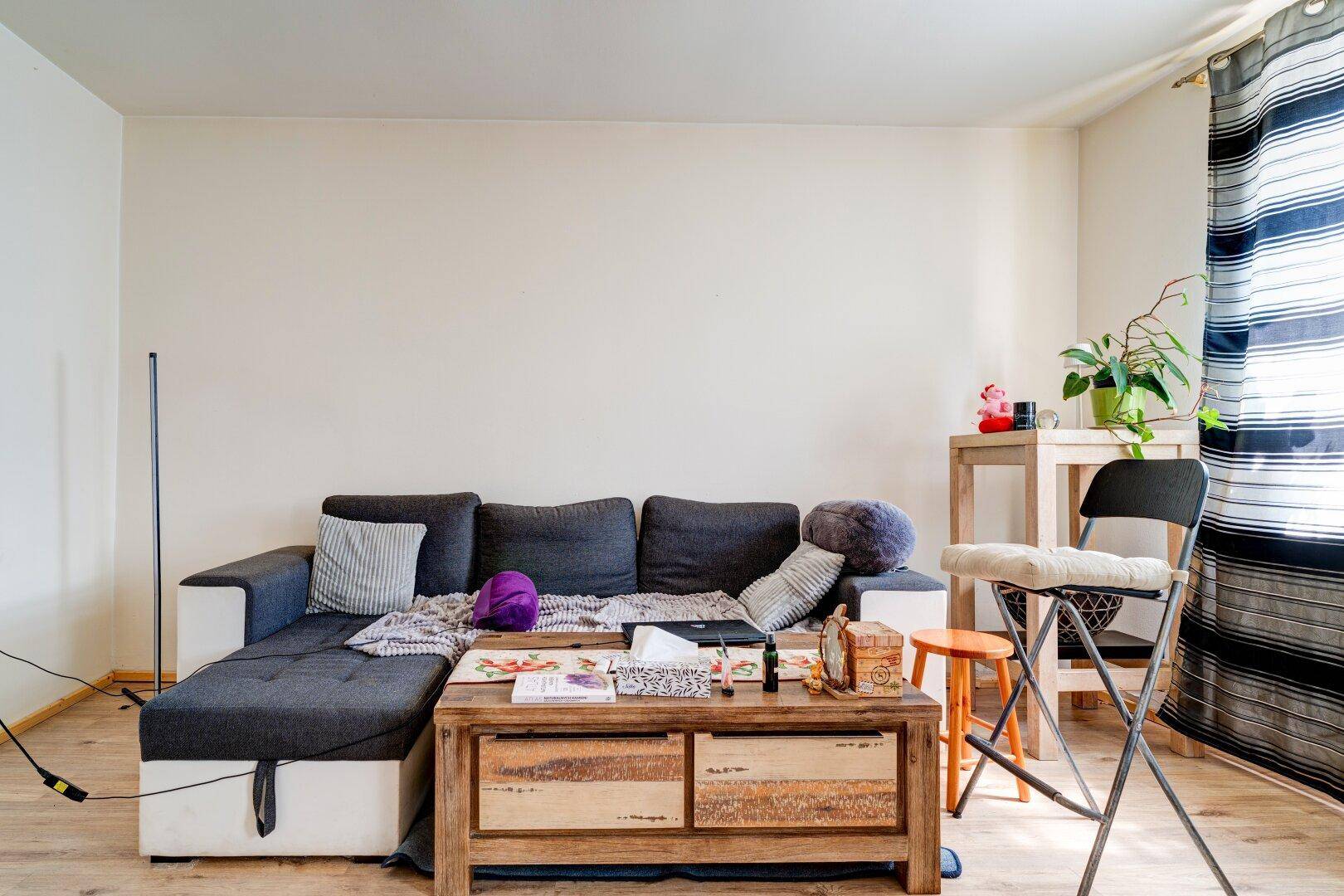 Gemütliches Wohnzimmer mit Ecksofa, Couchtisch und hellem Holzboden, ideal zum Entspannen.