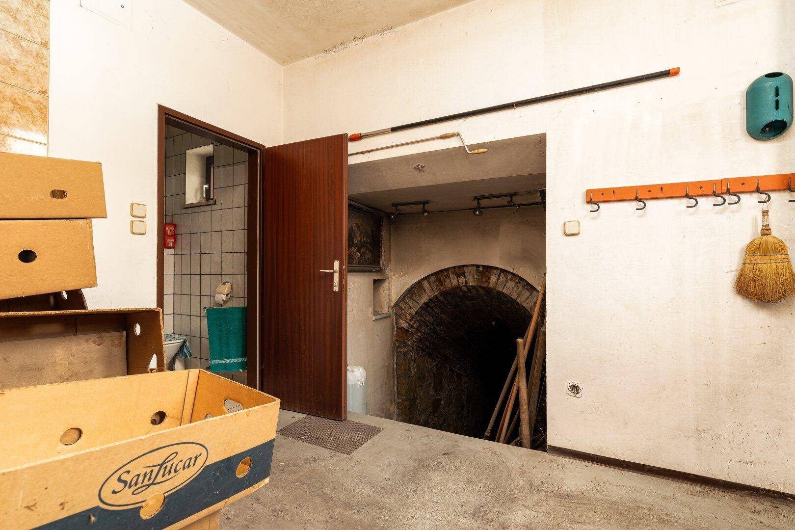 Eingang zu einem historischen Keller mit Ziegelgewölbe und angrenzendem WC-Bereich.