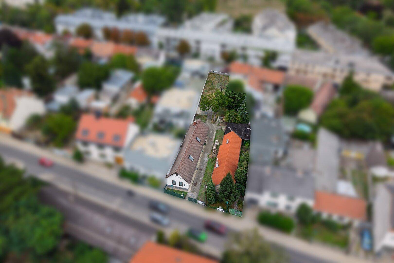 Blick von oben auf das Grundstück mit angrenzender Straße und umliegenden Häusern.