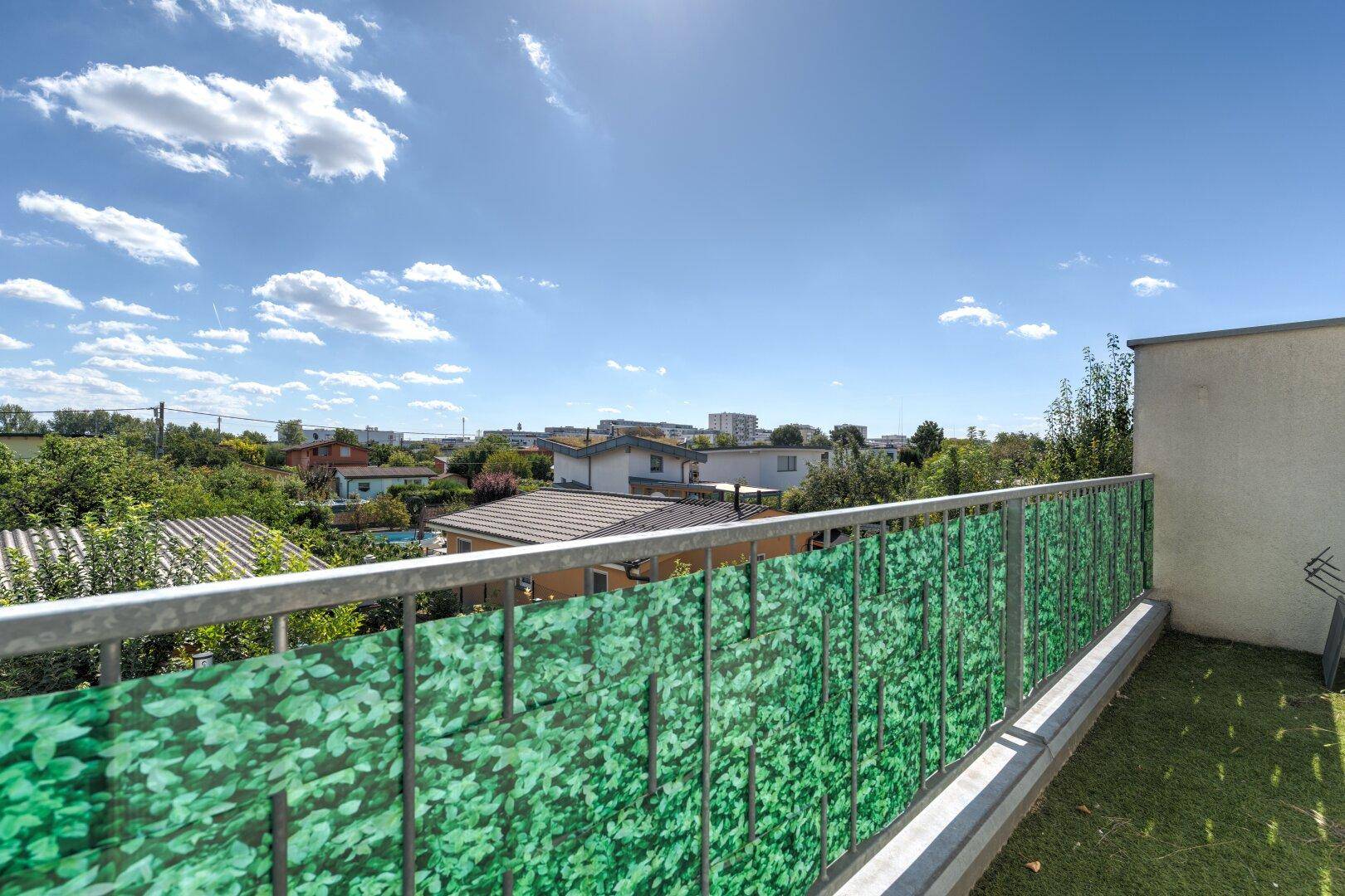 Geräumiger Balkon mit Kunstrasen und grüner Verkleidung, ideal für entspannte Stunden im Freien.