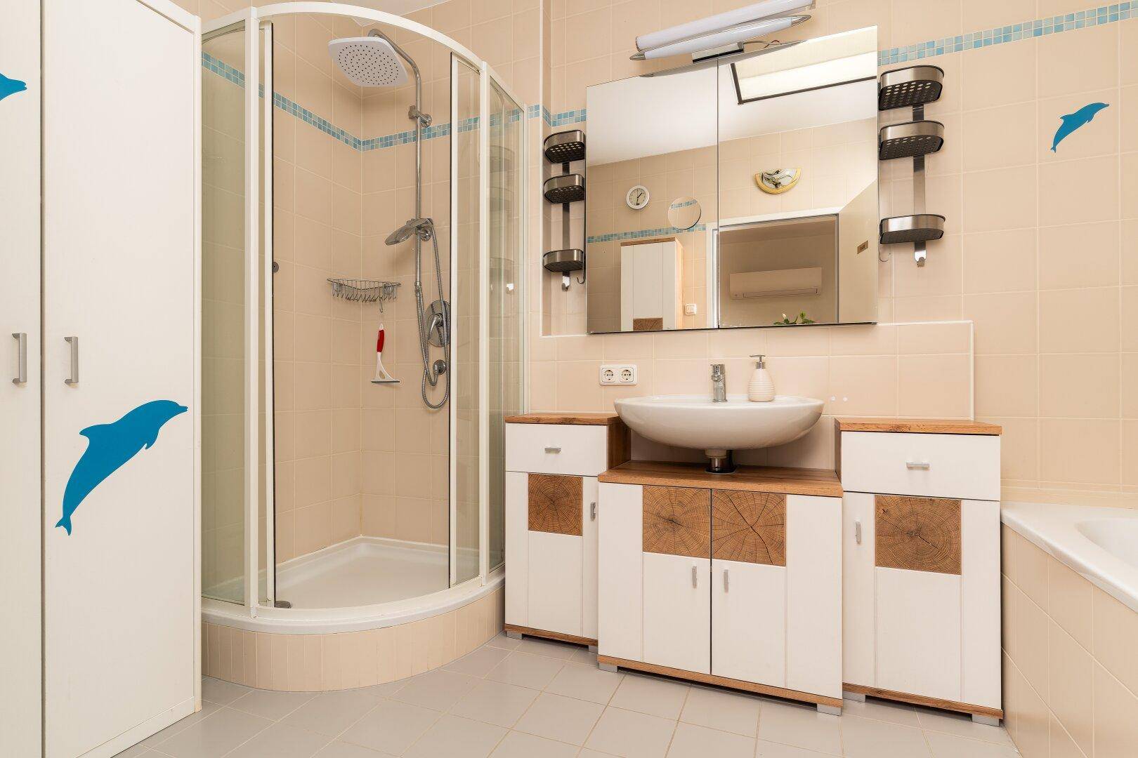 Helles Badezimmer mit beigen Fliesen, Eckdusche, Einzelwaschbecken und Badewanne.