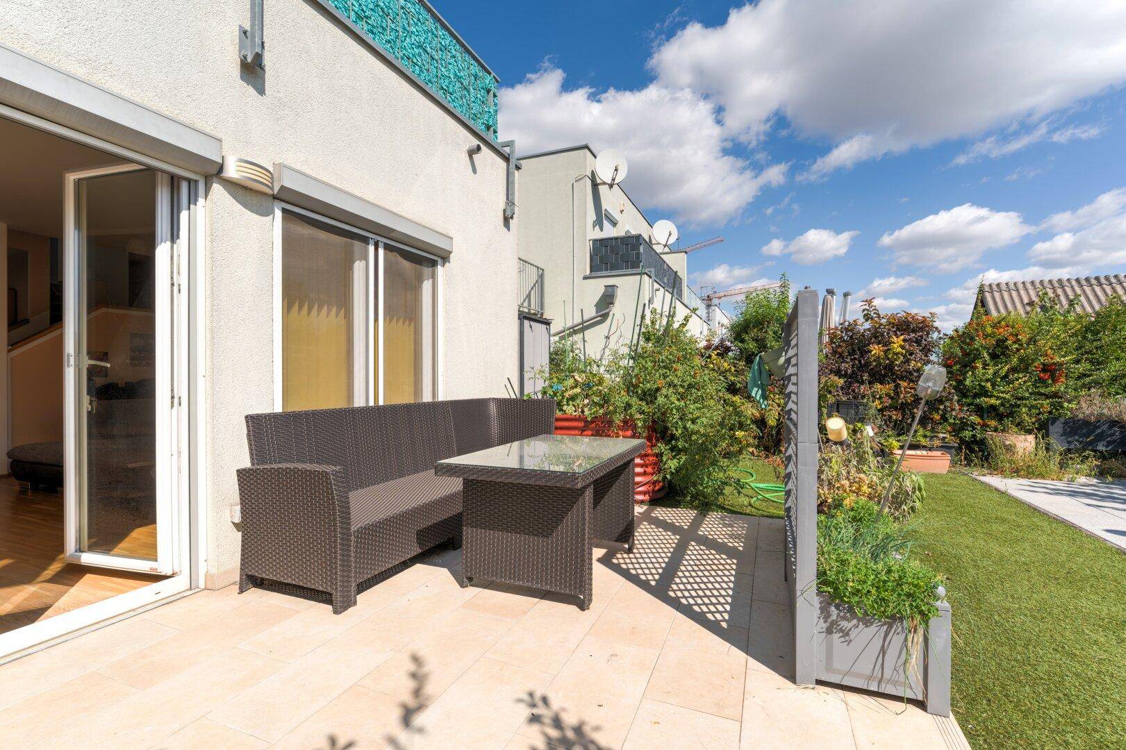 Gemütliche Terrasse mit Gartenmöbeln und direktem Zugang zum Haus, umgeben von Grün.