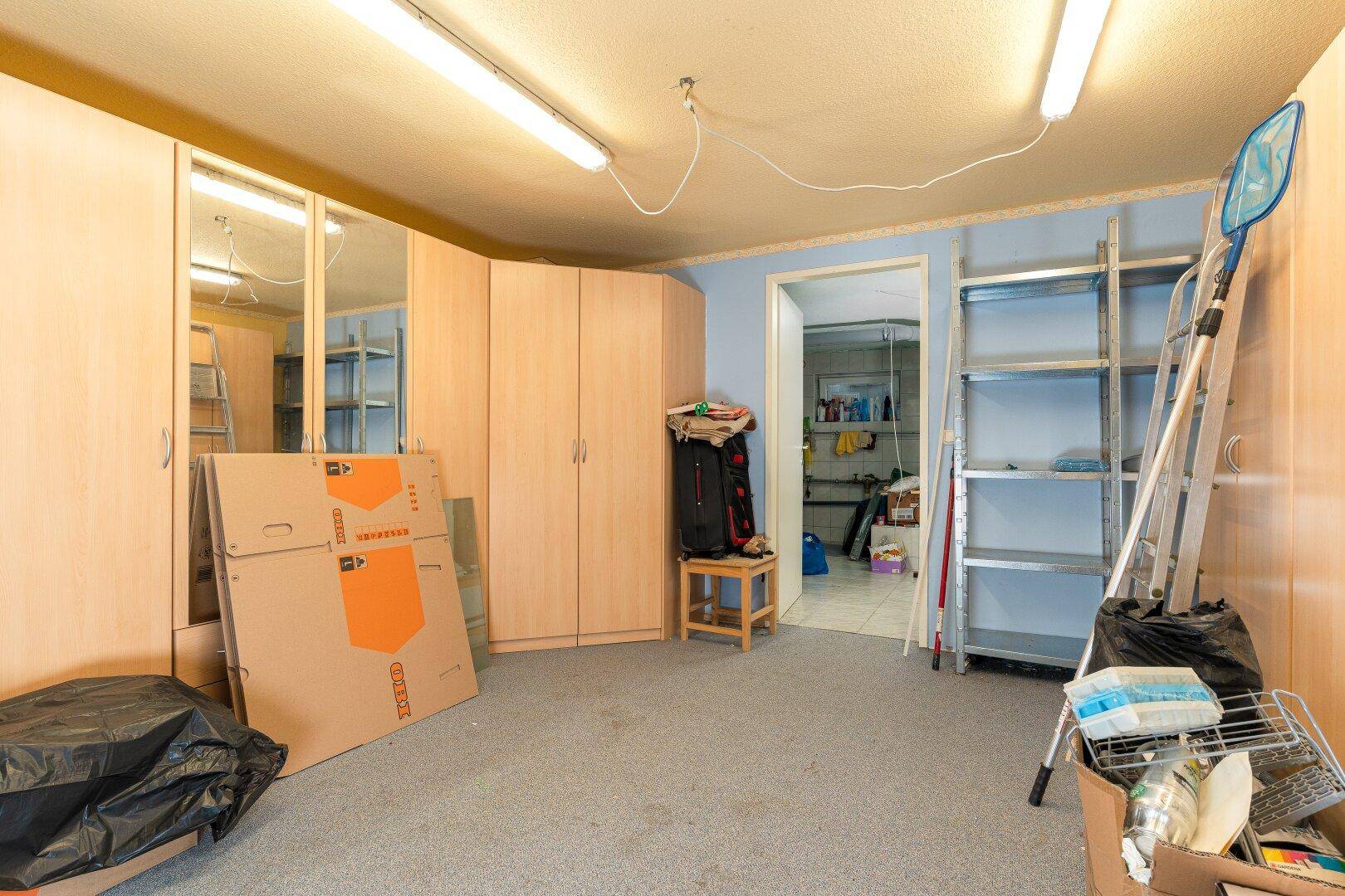 Geräumiger Abstellraum mit Teppichboden, hellen Schränken und Regalen für zusätzlichen Stauraum.