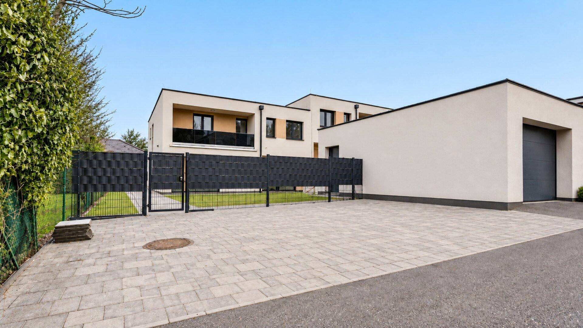 Zufahrt und Garage mit gepflastertem Vorplatz vor den modernen Reihenhäusern.