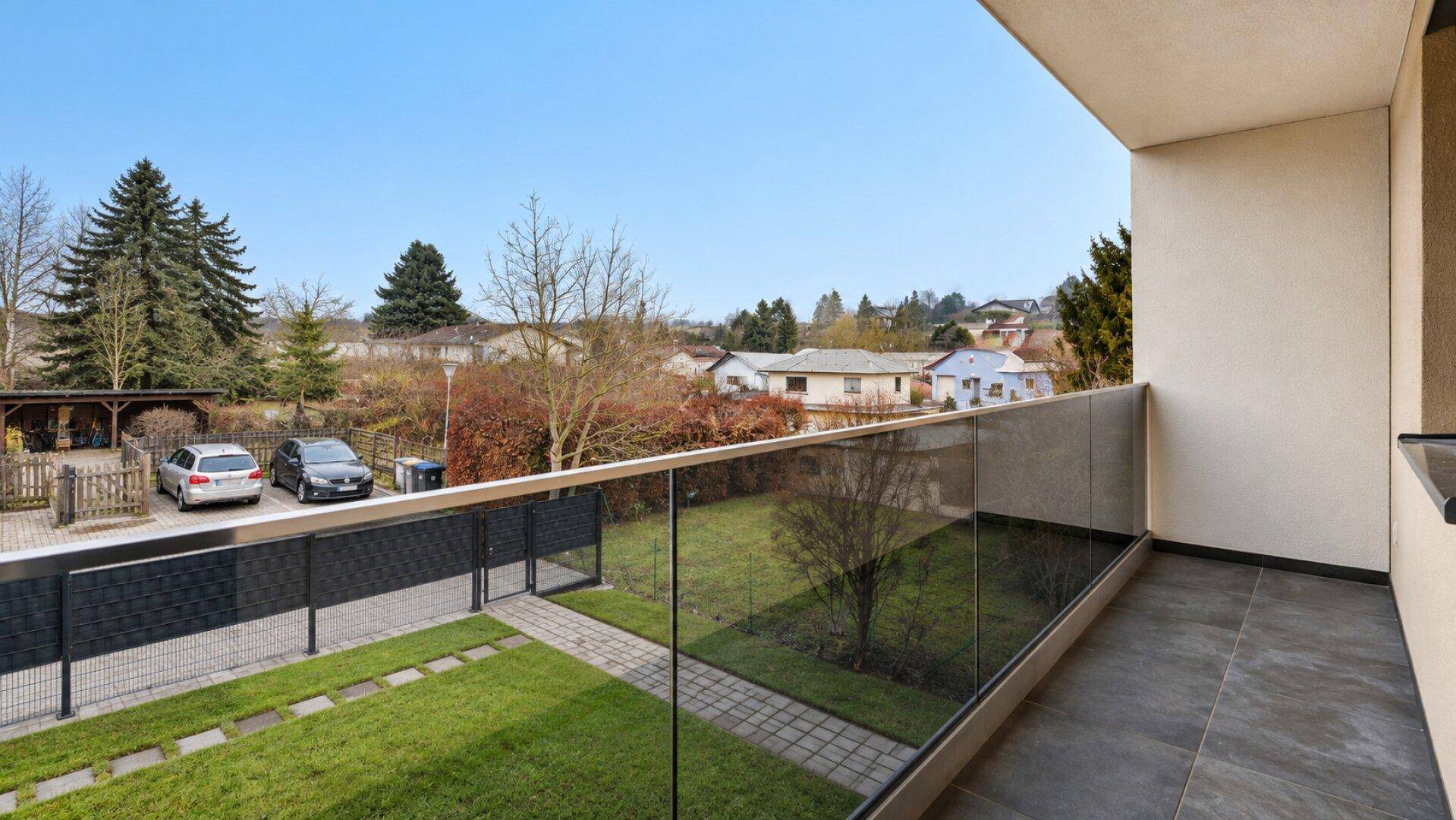 Geräumiger Balkon mit Glasgeländer und weitem Blick über die umliegende Wohngegend.