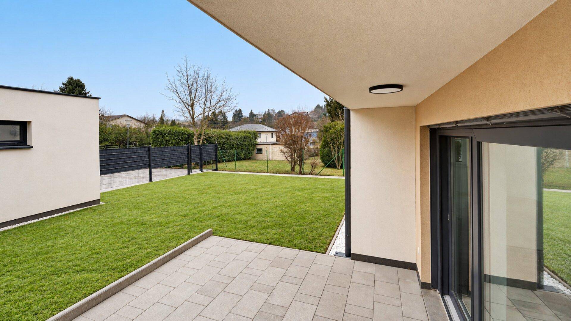 Sonniger Terrassenbereich mit Pflastersteinen und direktem Zugang zum privaten Garten.