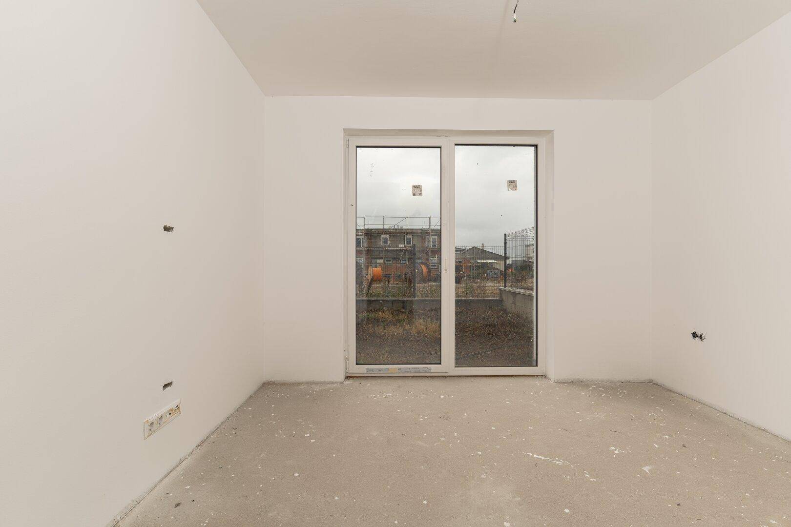 Heller Innenraum mit großen Fenstern und Blick auf die umliegende Baustelle.