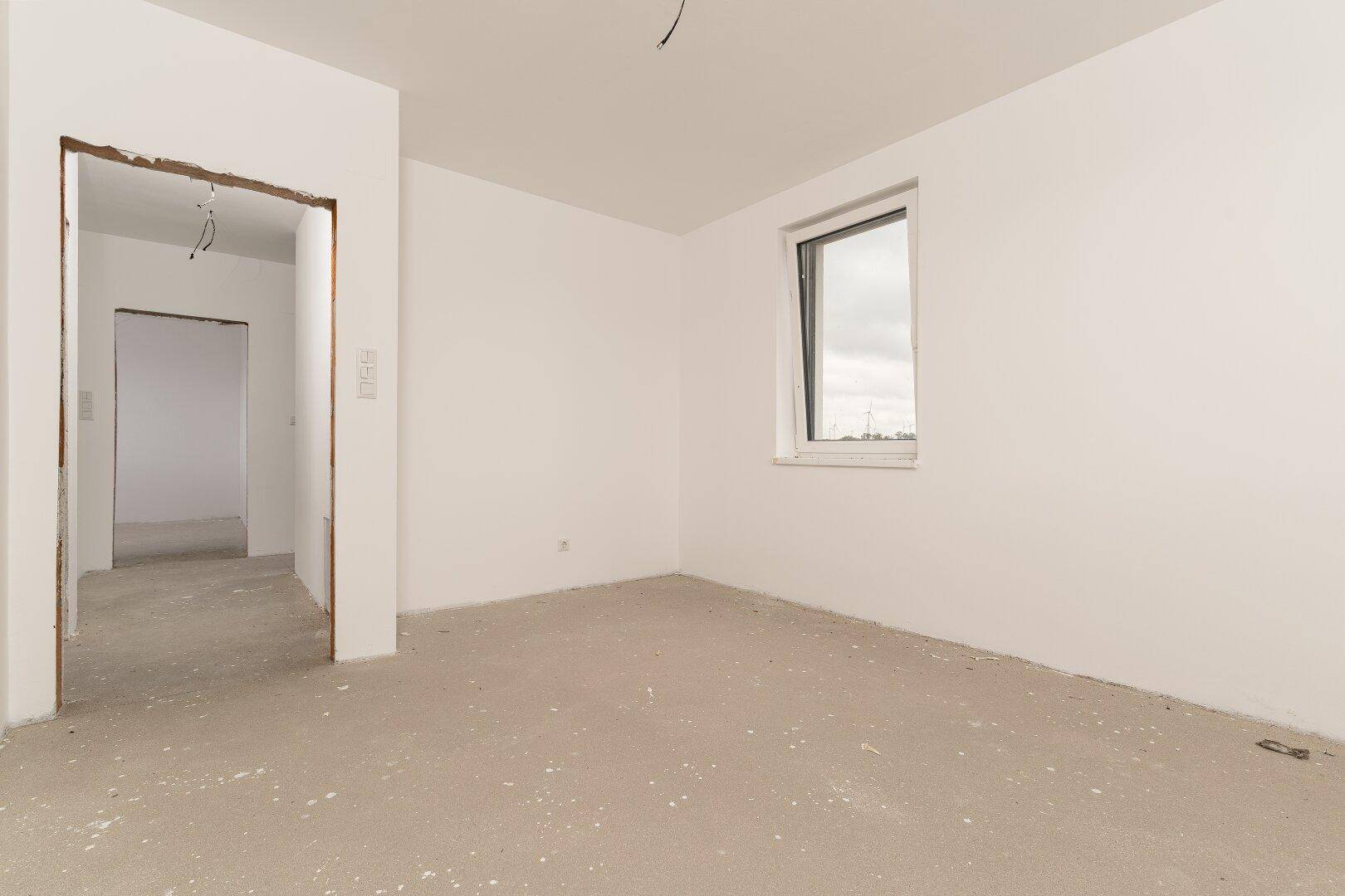 Unfertiges Zimmer mit einem Fenster und Zugang zu einem weiteren Raum.
