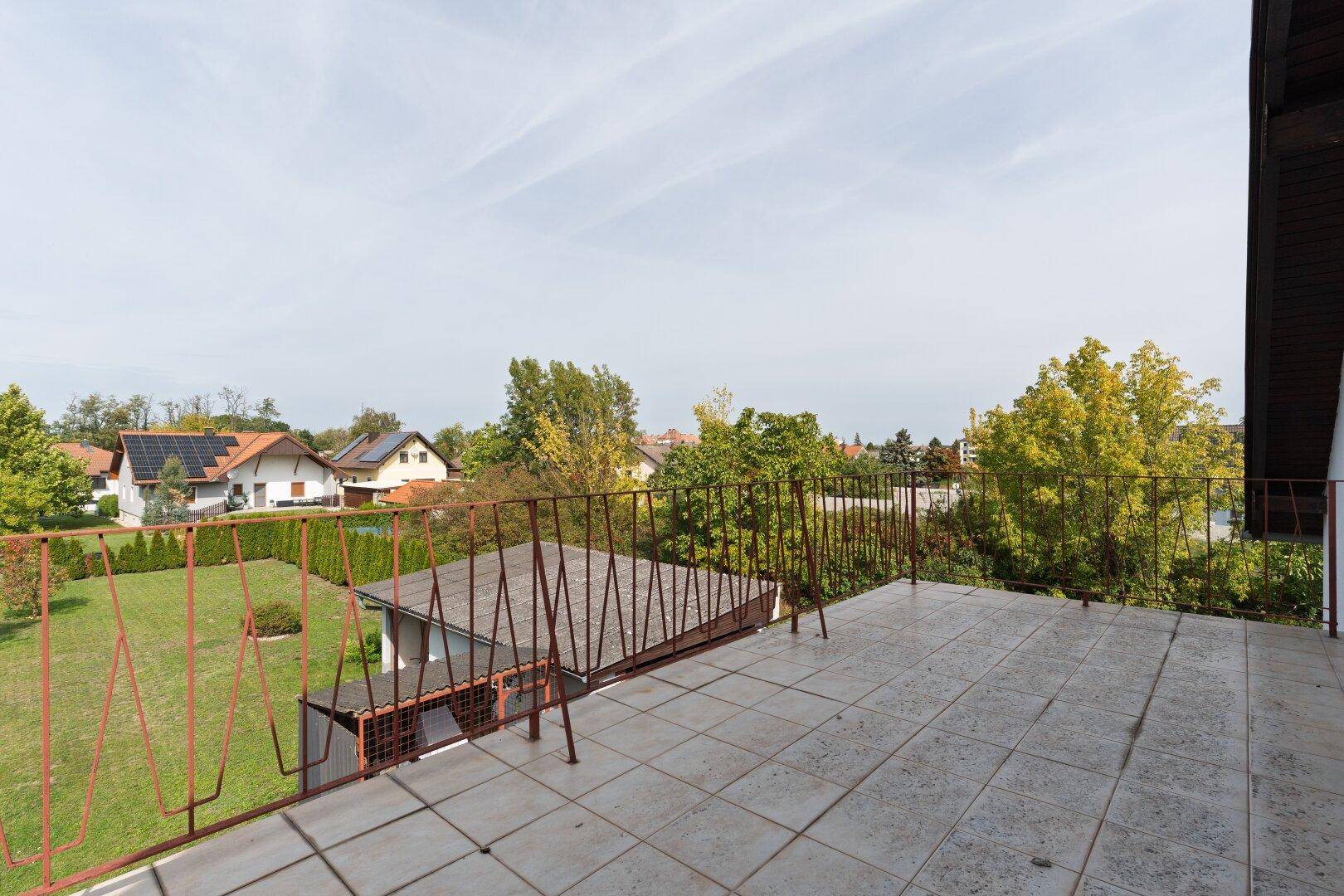 Geräumiger Balkon mit Fliesenboden und Blick auf die umliegenden Häuser und viel Grün.