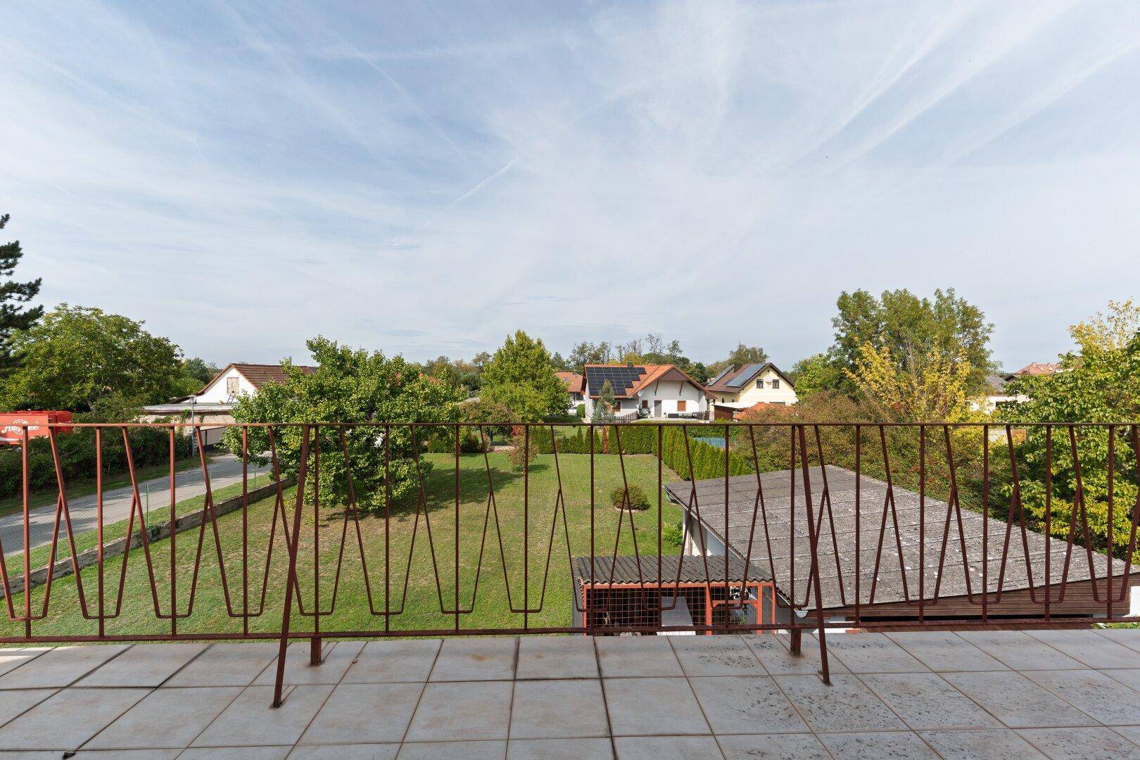 Sonniger Balkon mit weitem Ausblick auf den gepflegten Garten und die Nachbarschaft.