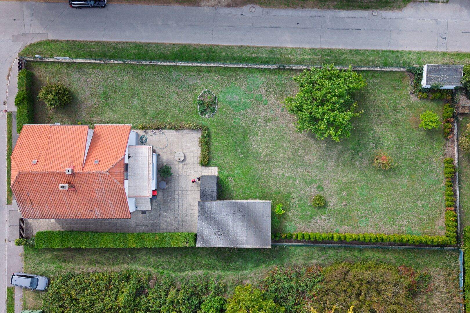 Detaillierte Luftaufnahme des Hauses und des großen Gartens mit gepflegter Hecke und Bäumen.