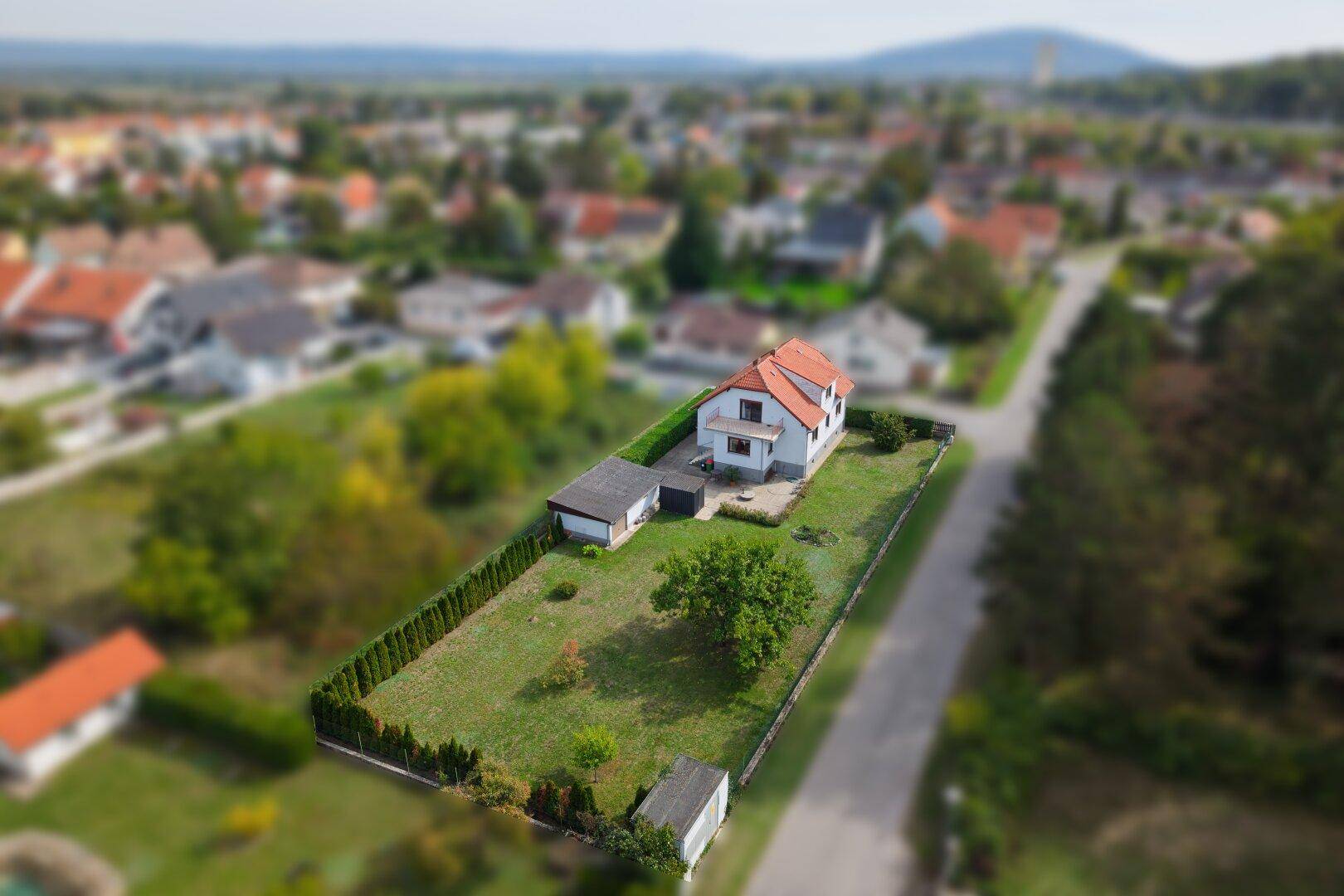 Luftaufnahme eines Einfamilienhauses mit großem Garten und umliegender Wohnsiedlung.